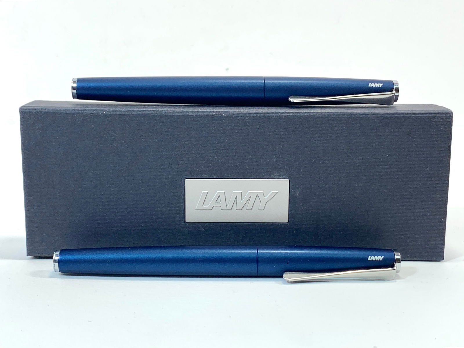 Lamy German Blue Enamel and Chrome Fountain and Ballpoint Pair w/Box: Excellent single use cosmetic condition, with the fountain pen cap glued on with old ink. Needs to be soaked. Approx. 5 3/8". Glossy finish throughout. Box may show moderate shelf wear, and may includ