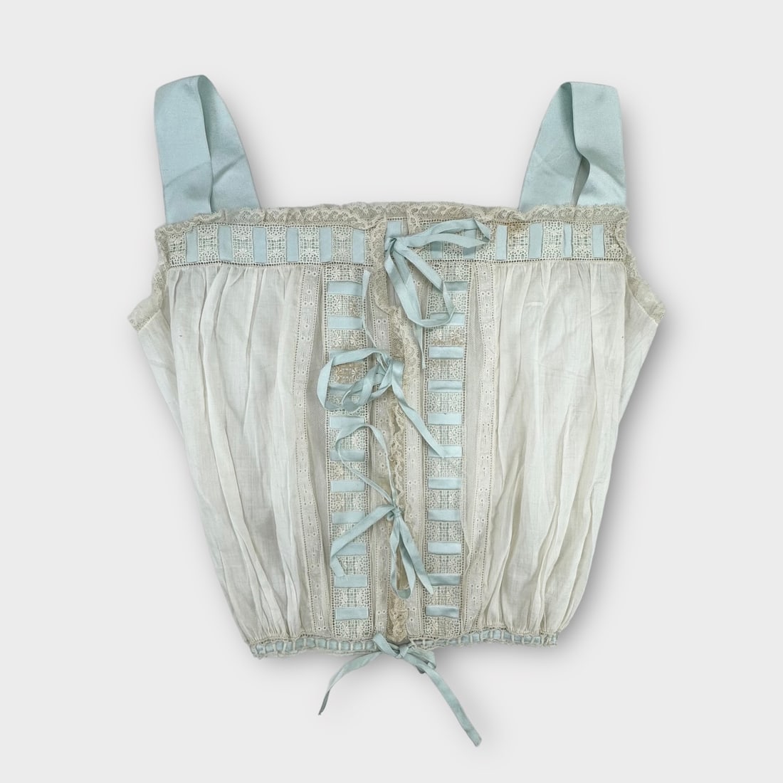 Antique Victorian Chemise or Camisole. Delicate Cotton with Lace and Pale Blue Ribbon Straps and: 2 Spots on lace in front. Tiny spots on back and tiny holes near hemline. Measurement taken flat. Chest 17 in. Waist 10 in. Shipping: We do not provide in-house shipping or packing. Please reach out t