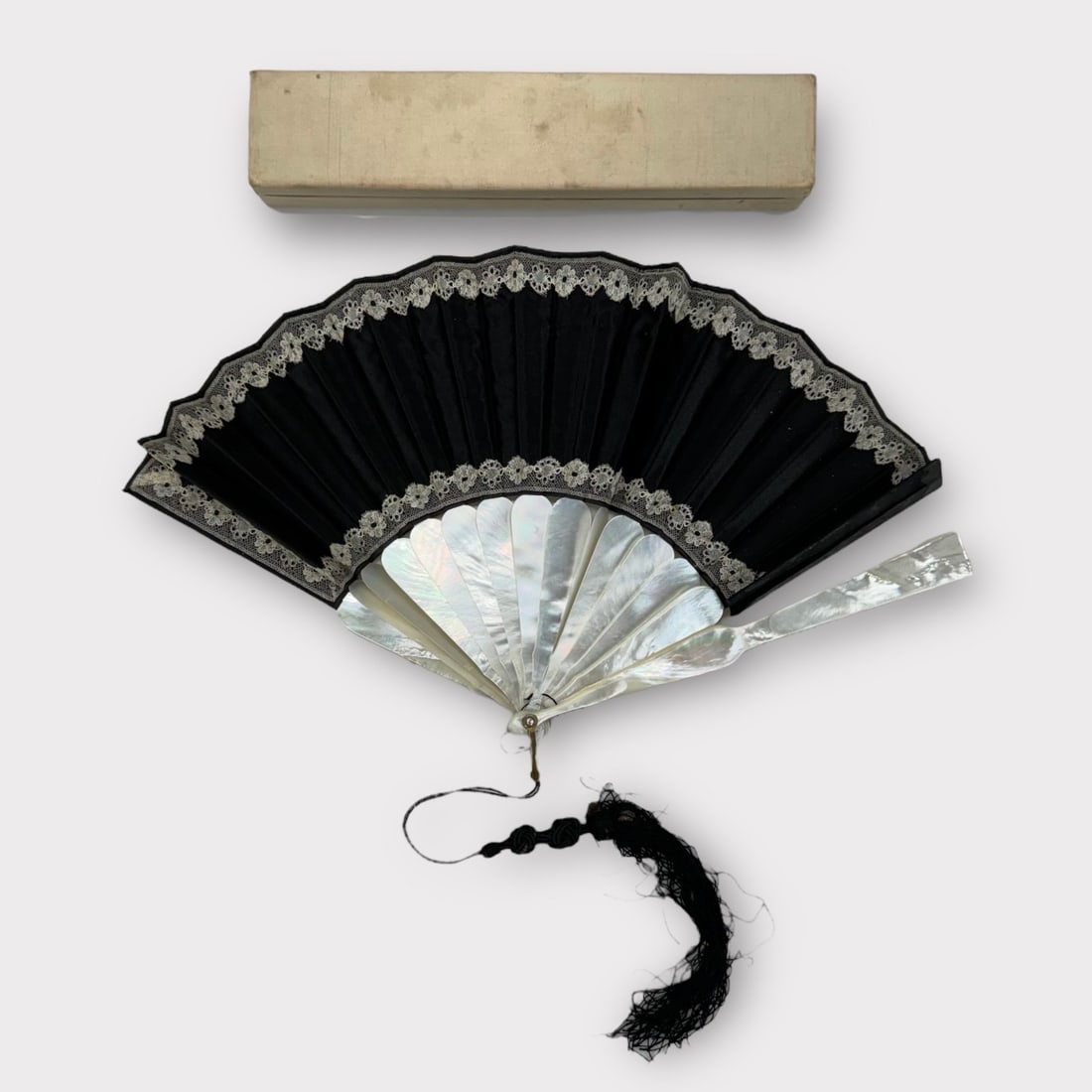 Mother of Pearl, Black Silk, and Lace Hand Fan with Rhinestone and Tassel Detail. In Silk Box.: Fan is not mechanically sound and silk tassel is degrading.