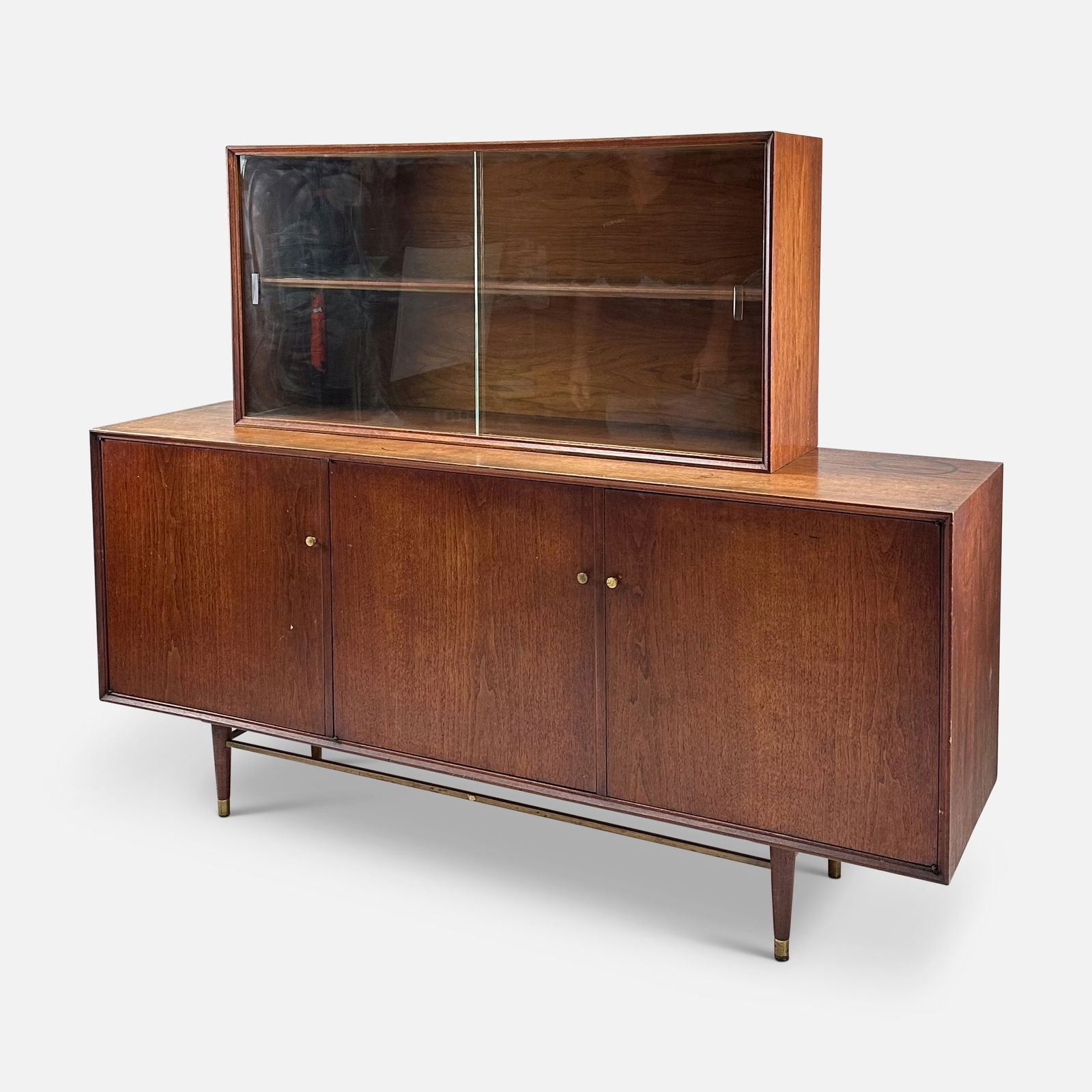 Furnette N. Y. Two-Piece Dark Wood Lighted Display Credenza: Furnette N. Y. two-piece dark wood lighted display credenza. Ca. 1960s. Good age-appropriate condition, with shown surface water stains. We do not provide in-house shipping! Please reach out to Donald