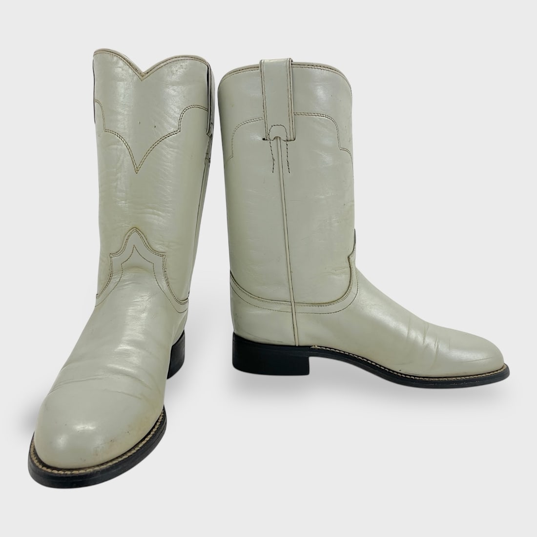 Vintage Tony Lama Ladies Size 6B White Leather Cowboy Boots: Vintage Tony Lama White Leather Cowboy Boots w/ Smooth Leather Upper, Scalloped Collar, Pull Straps, Black Outsoles, And Stacked Heel, Showing Light Wear On Soles And Creasing On Leather. We do not pr