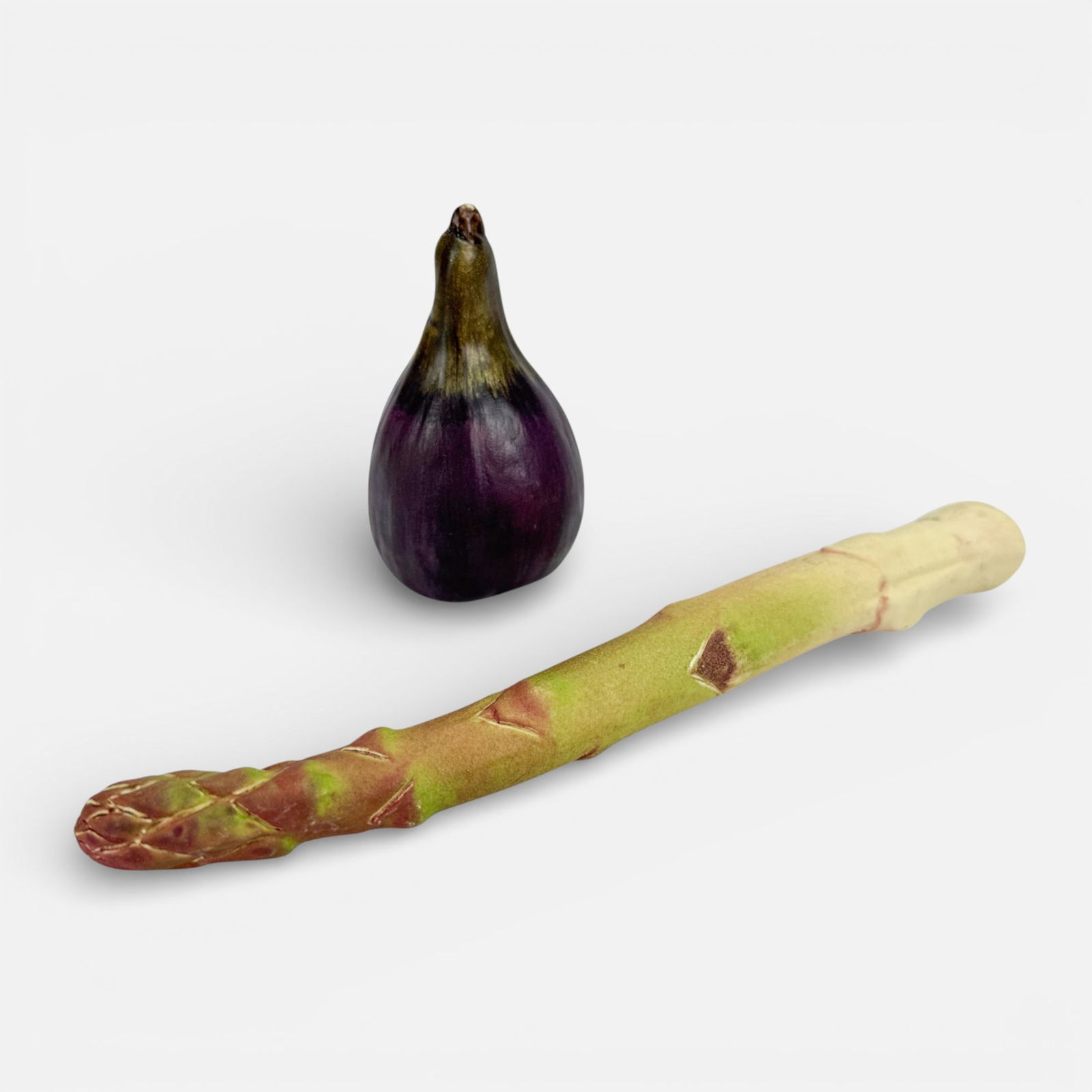 Mary Kirk Kelly Realistic Ceramic Eggplant and Asparagus Vegatable Sculptures: Mary Kirk Kelly (American, 1918-2013), plum signed, impressed mark to celery. Included dimensions for asparagus.For shipping, we highly recommend Donald Camden at UPS Store 4608. Alternatively, reach