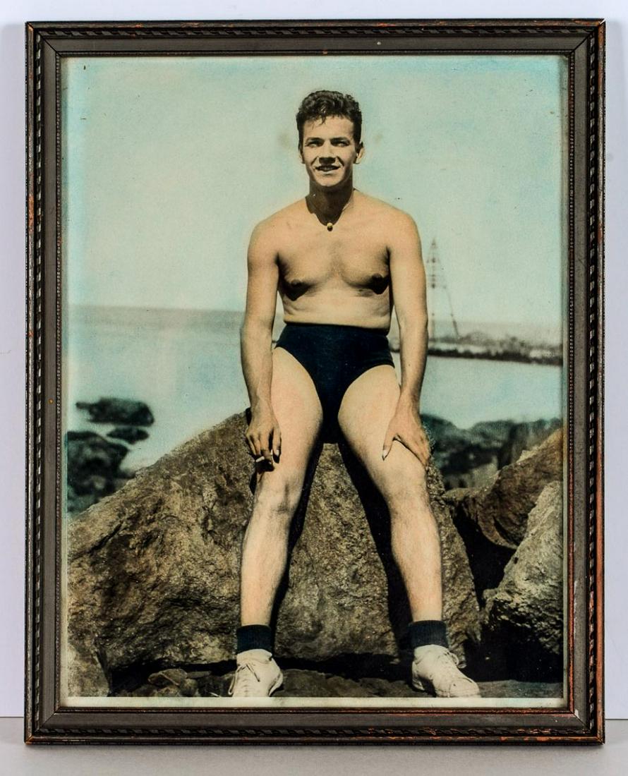 Man in bathing suit and sneakers, 1940s: Colored photograph of a man wearing a bathing suit and sneakers and smoking circa 1940s. Gay interest. Size: Framed dimensions 12"x15". Can be shipped without frame to save on shipping.