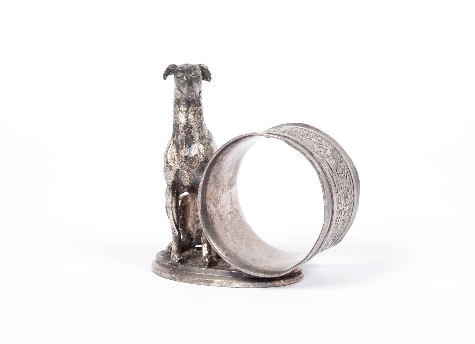 REED & BARTON ITALIAN GREYHOUND NAPKIN RING: REED & BARTON ITALIAN GREYHOUND NAPKIN RINGNumber #1485, stamped underfoot. Relief decoration of birds and florals to ring, resting astride a sitting greyhound, all atop an ovular base. 3.25" height