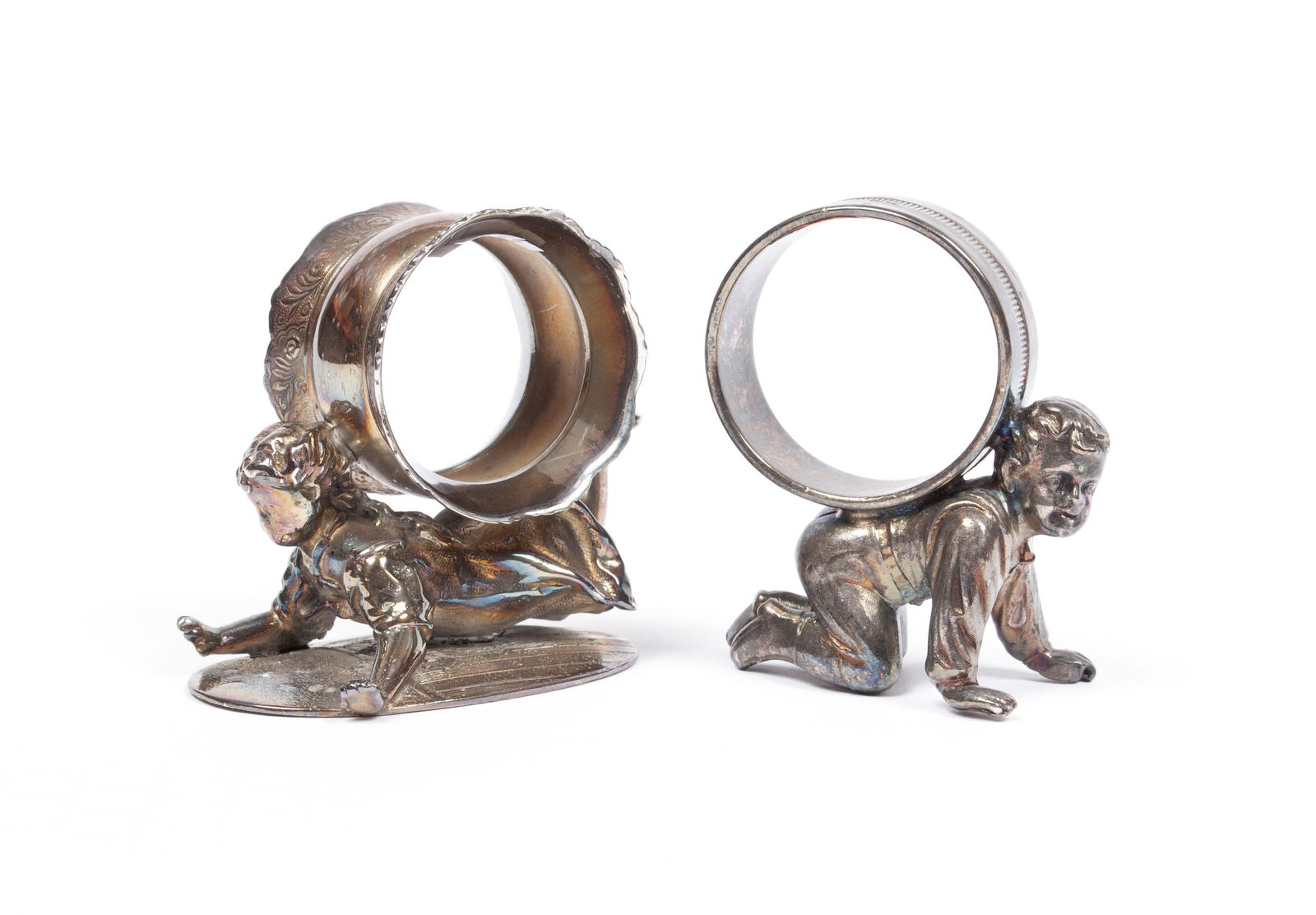 TWO CRAWLING CHILDREN NAPKIN RINGS: TWO CRAWLING CHILDREN NAPKIN RINGSBoth quadruple plated, a boy and girl on hands and knees with the rings on their backs. The girl a Wilcox, #01548, with floral decoration to barrel form ring, atop an