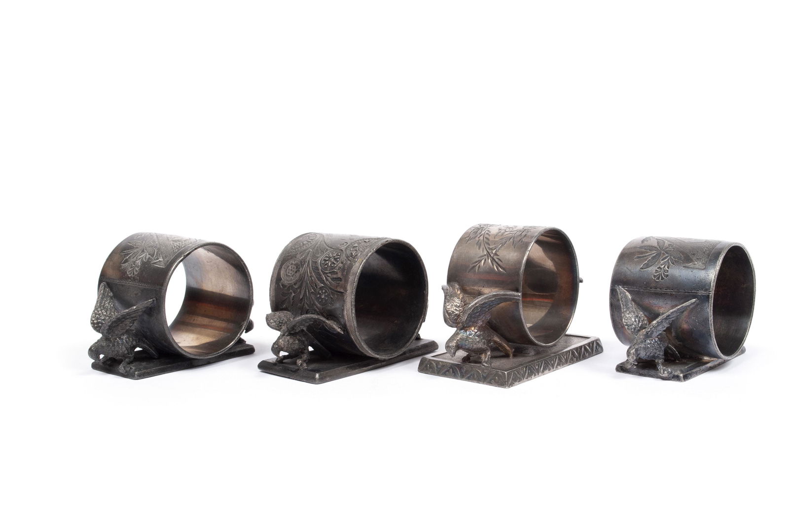 FOUR BIRD-FLANKED NAPKIN RINGS: FOUR BIRD-FLANKED NAPKIN RINGSNear identical models, all flanked by birds and atop rectangular bases. One a Meriden #146, one a Middletown #74, one a Toronto #1144, and one a West Meriden/Rogers Smith