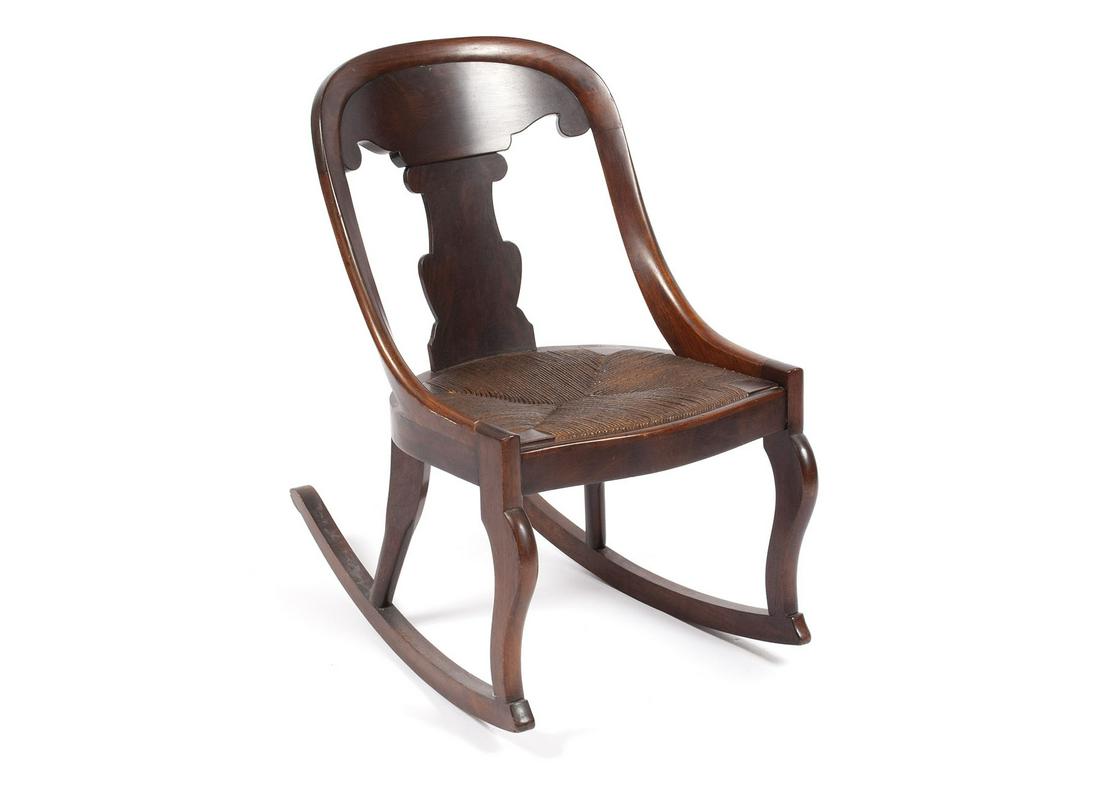 CLASSICAL REVIVAL ROCKING CHAIR: CLASSICAL REVIVAL ROCKING CHAIRAmerican, 3rd quarter 19th century, mahogany. Concave back with solid vasiform splat, over the woven rush seat. 29" height, 18" width