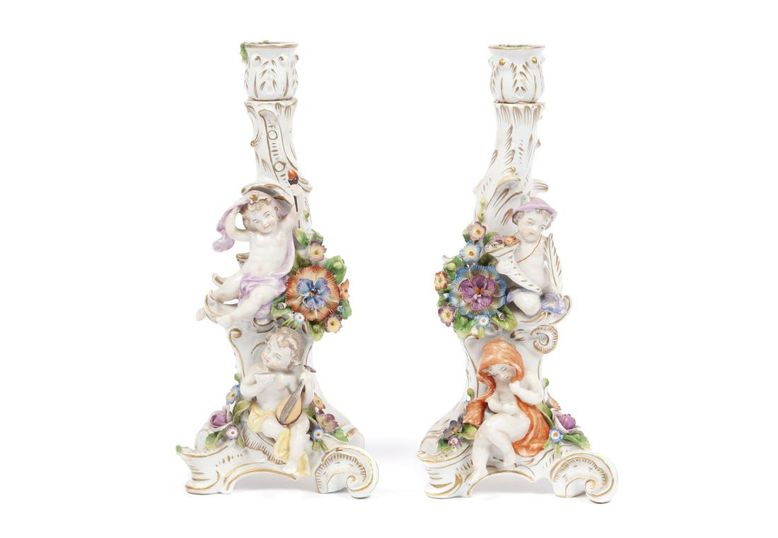 PAIR OF NYMPHENBURG PORCELAIN CANDLESTICKS: PAIR OF NYMPHENBURG PORCELAIN CANDLESTICKS Germany, early 20th century, porcelain. Brightly painted floral relief and putti to Rococo style sticks, marked to underside. 10.75" height