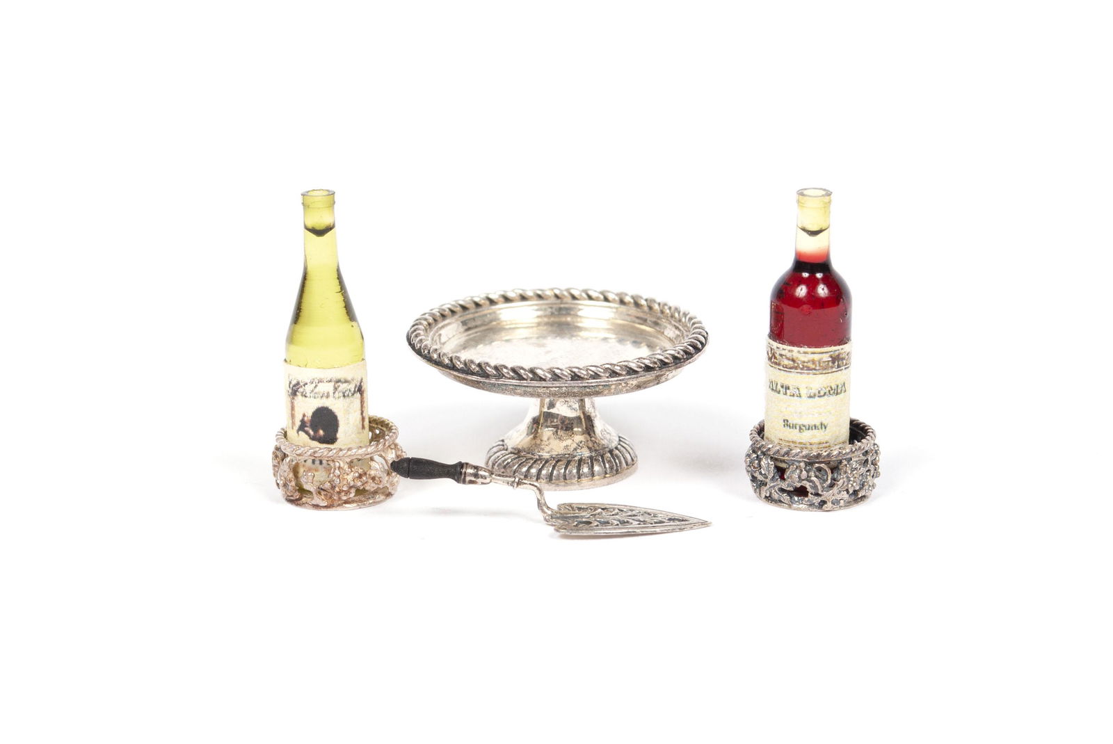 OBADIAH FISHER MINIATURE STERLING TABLEWARE: OBADIAH FISHER MINIATURE STERLING TABLEWAREFinely crafted diminutive sterling silver wine coasters, cake stand, and server all by Obadiah Fisher, with two bottles of wine. Weighing 10 grams altogether