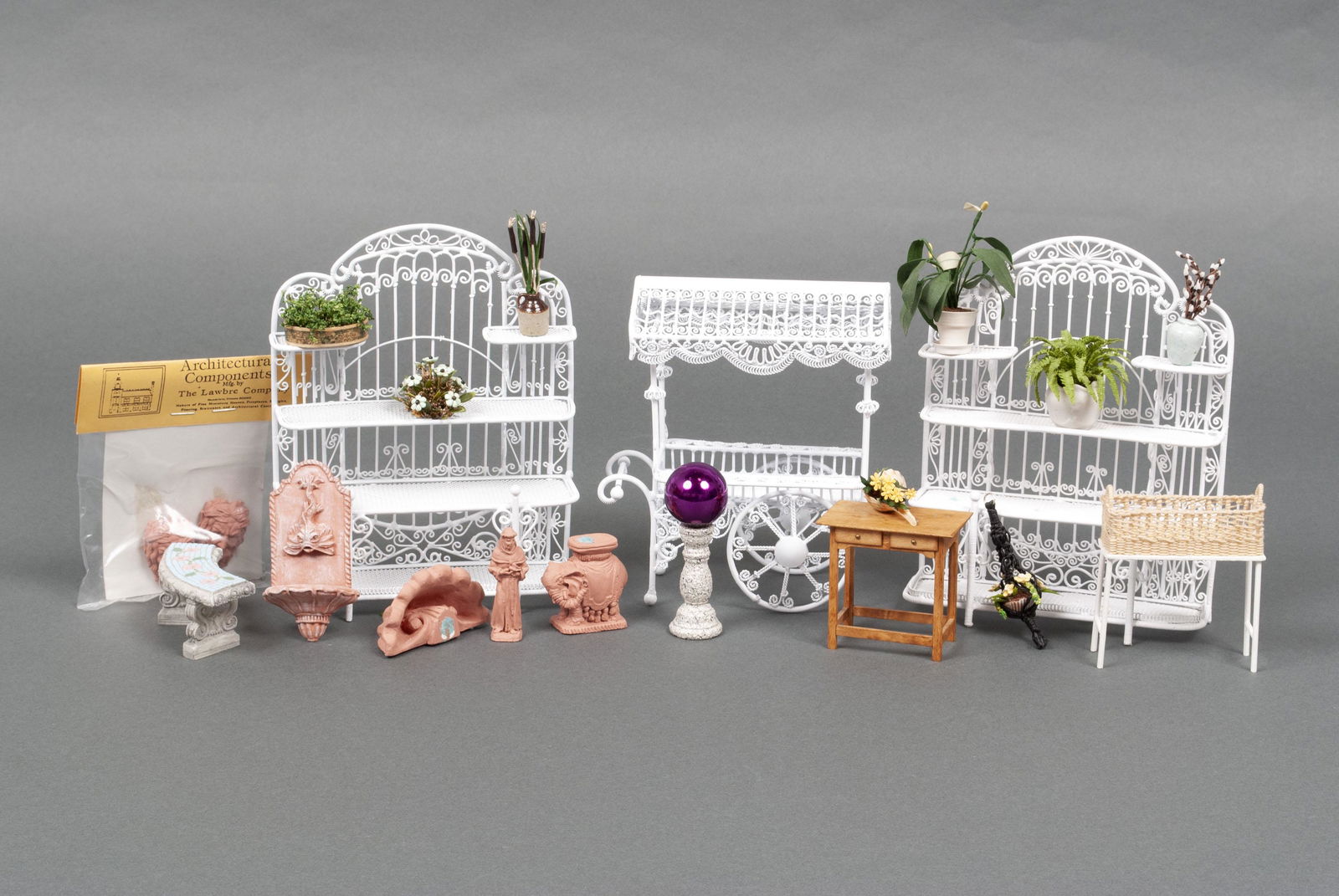 ASSORTMENT OF FLORAL MINIATURES: ASSORTMENT OF FLORAL MINIATURESConsisting of a pair of white wired shelving units and white wired flower cart, mosaic garden bench, wicker basket stand, wooden side table, a variety of terracotta gard
