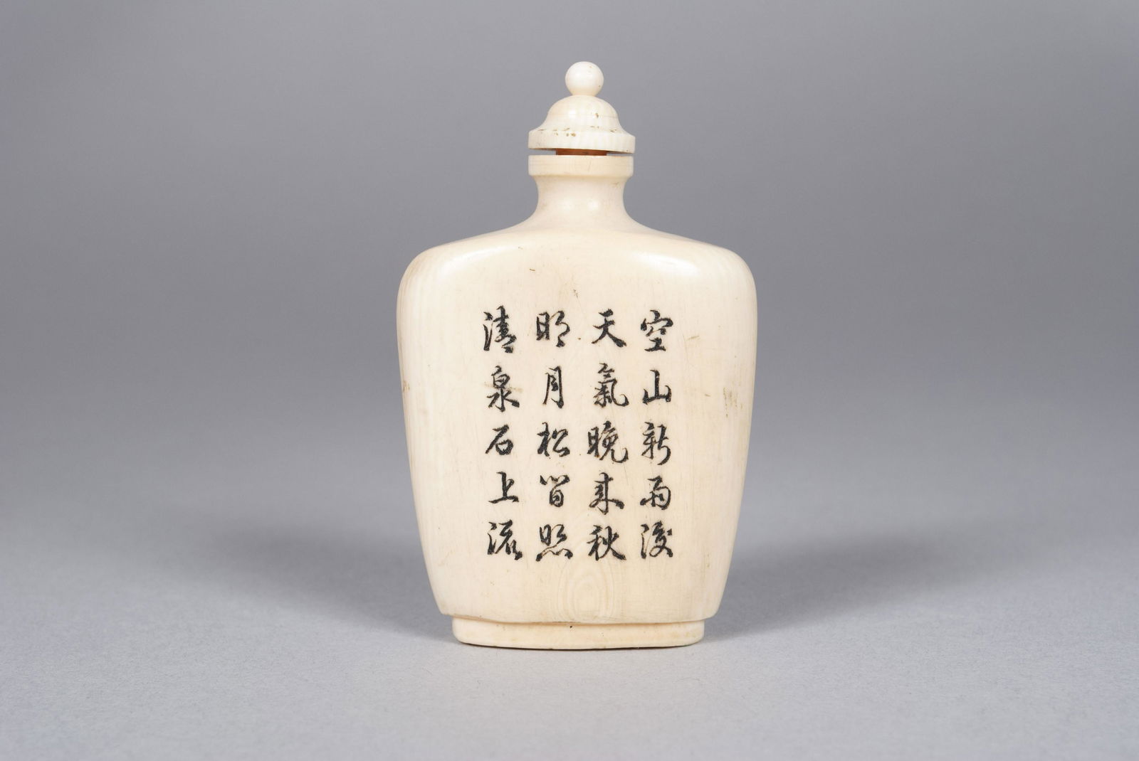 CARVED DRAGON AND POEM SNUFF BOTTLE: CARVED DRAGON AND POEM SNUFF BOTTLEChina, 19th century. Masterfully incised poem by Wang Wei to one side and the other carved with dragon amongst clouds in relief panel, stepped and recessed oval foot