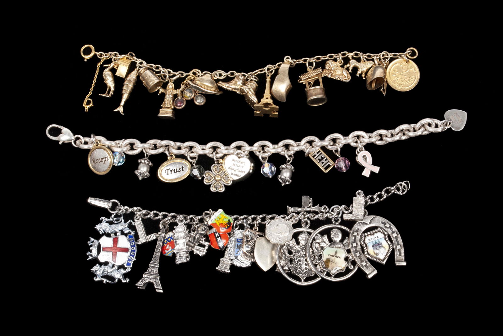 TRIO OF CHARM BRACELETS: TRIO OF CHARM BRACELETSOne traveler's bracelet with mostly European tourist charms, one large-linked chain mostly with words of affirmation and glass bead accents, and one bracelet with assorted gold