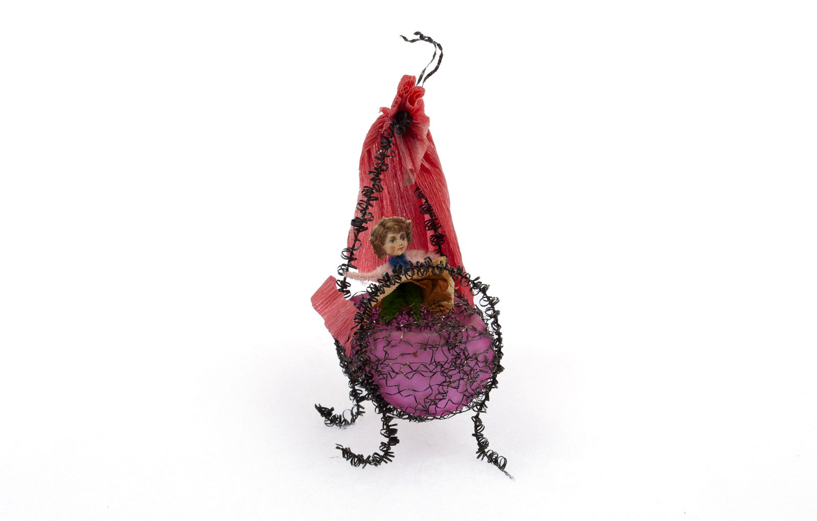 SEBNITZ CHRISTMAS ORNAMENT: SEBNITZ CHRISTMAS ORNAMENT Germany, pre-1950. Constructed of scrap with a baby in a cradle, all in shades of red. 5" height