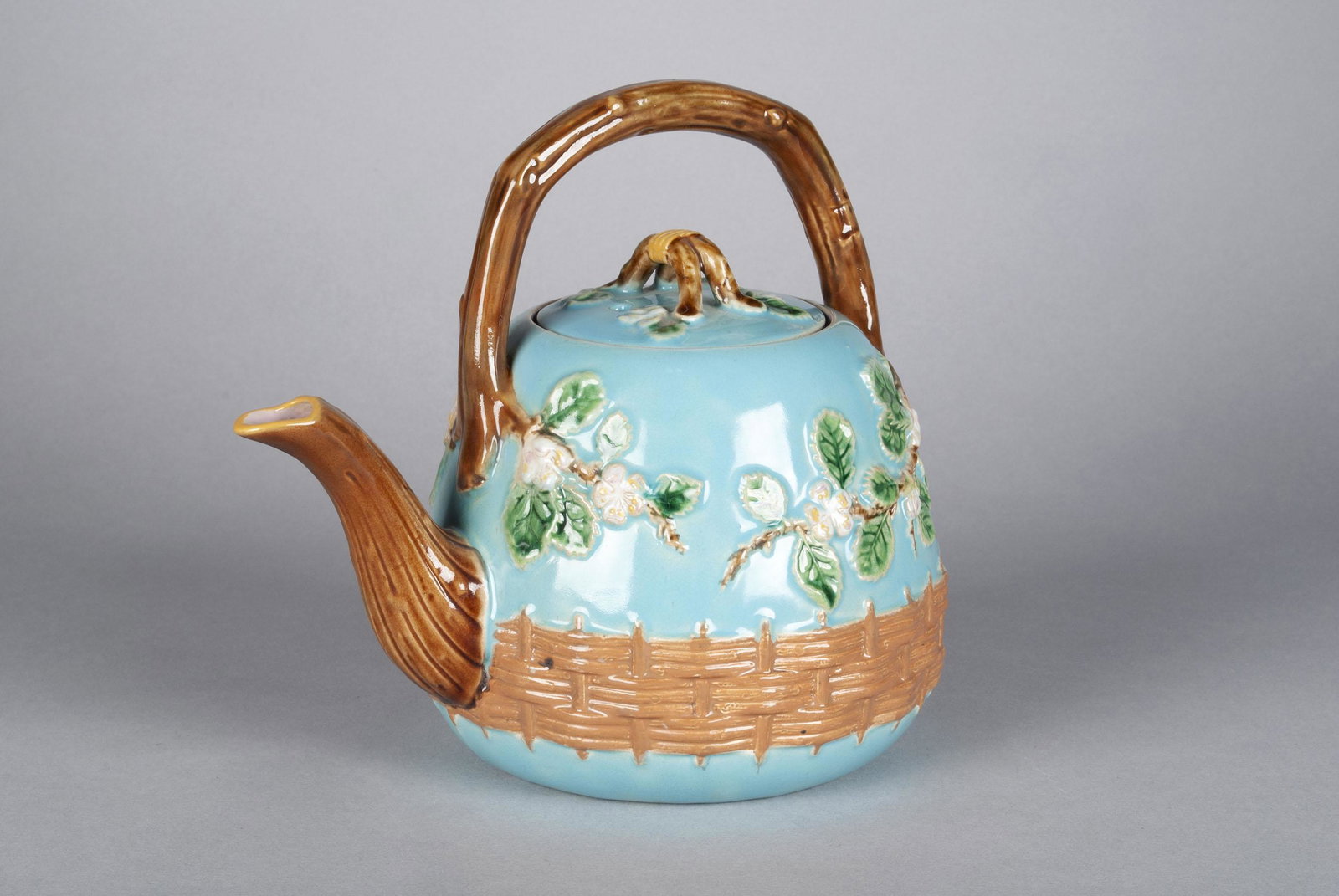 MAJOLICA APPLE BLOSSOM TEAPOT BY GEORGE JONES: MAJOLICA APPLE BLOSSOM TEAPOT BY GEORGE JONES England, circa 1870, teapot having branch-form handle with raised apple blossom and basket weave decoration, marked underfoot "5304A" and diamond registry