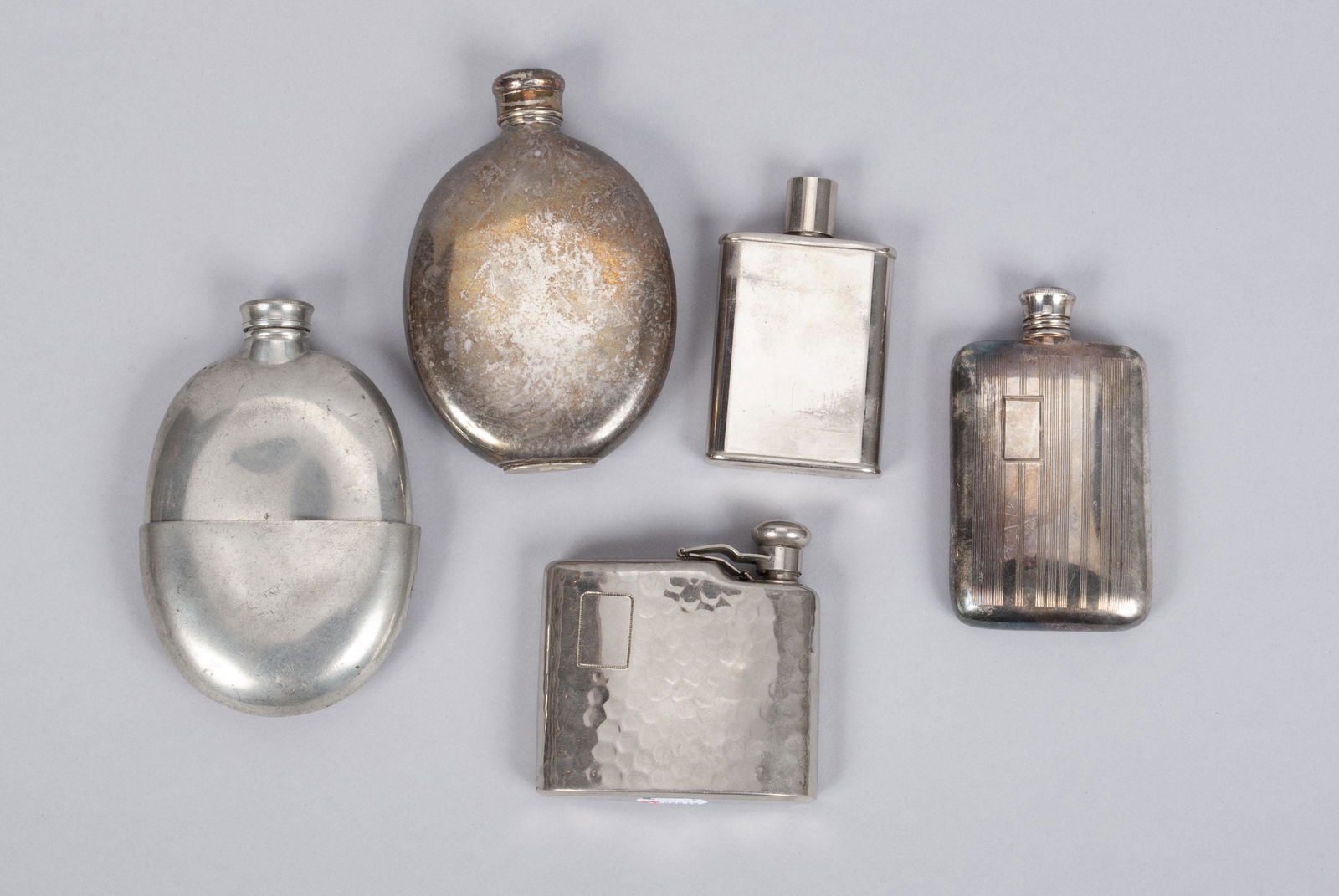 FIVE PEWTER AND PLATED FLASKS: FIVE PEWTER AND PLATED FLASKSOf varying form and design, one marked Germany.