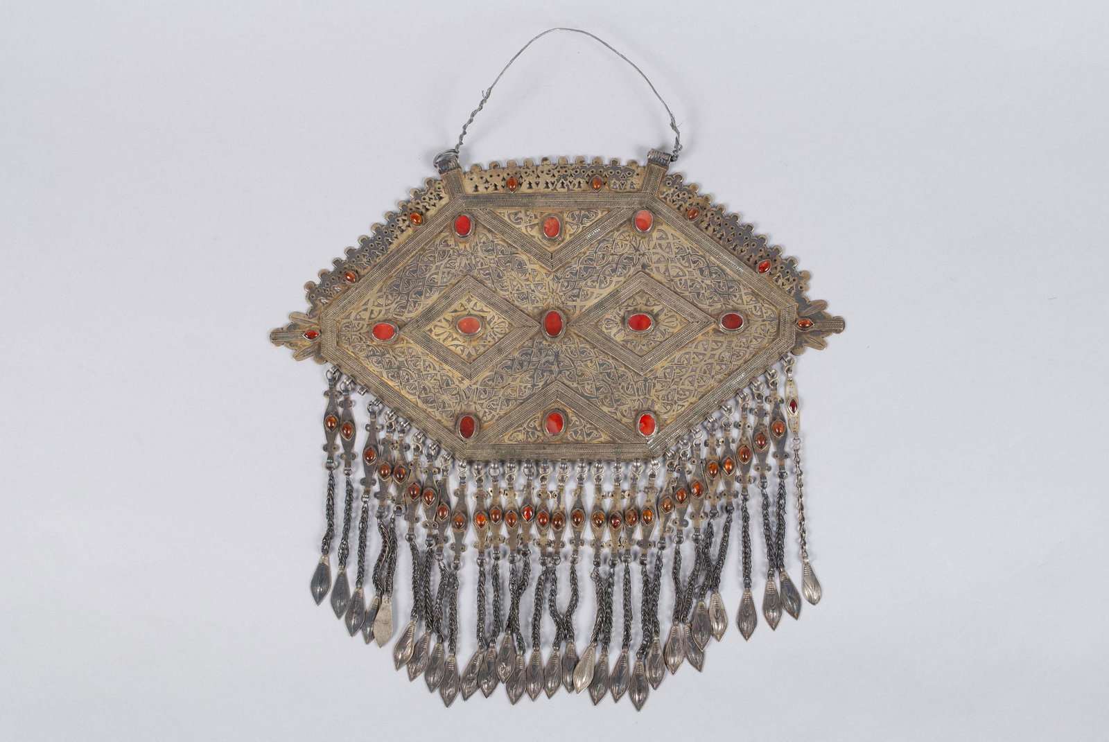 TURKOMAN SILVER AND CARNELIAN BREASTPLATE: TURKOMAN SILVER AND CARNELIAN BREASTPLATE Teke, Turkoman, nineteenth century. Gilt silver in hexagonal form with diamond design accented by eleven carnelians, underscored with linked chain and amber p