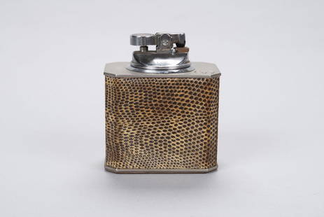 GUCCI TABLE LIGHTER: GUCCI TABLE LIGHTERThe body wrapped snakeskin with impressed inverted Gucci logo to the top, the inset lighter with Colibri mark to underside, the button with lion and bird crest. 3.5" height