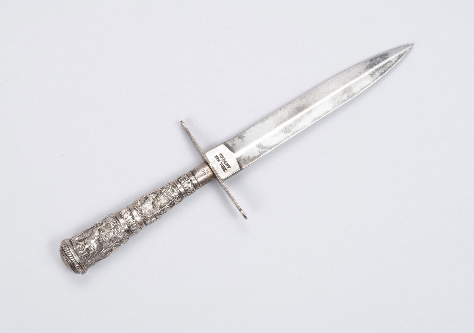 TIFFANY STAMPED DAGGER AND PRESENTATION BOX: TIFFANY STAMPED DAGGER AND PRESENTATION BOXAmerican, early 20th century, marked Tiffany near the hilt. The handle repousse decorated with scenes of animals, marked "06". Housed within fitted case bear