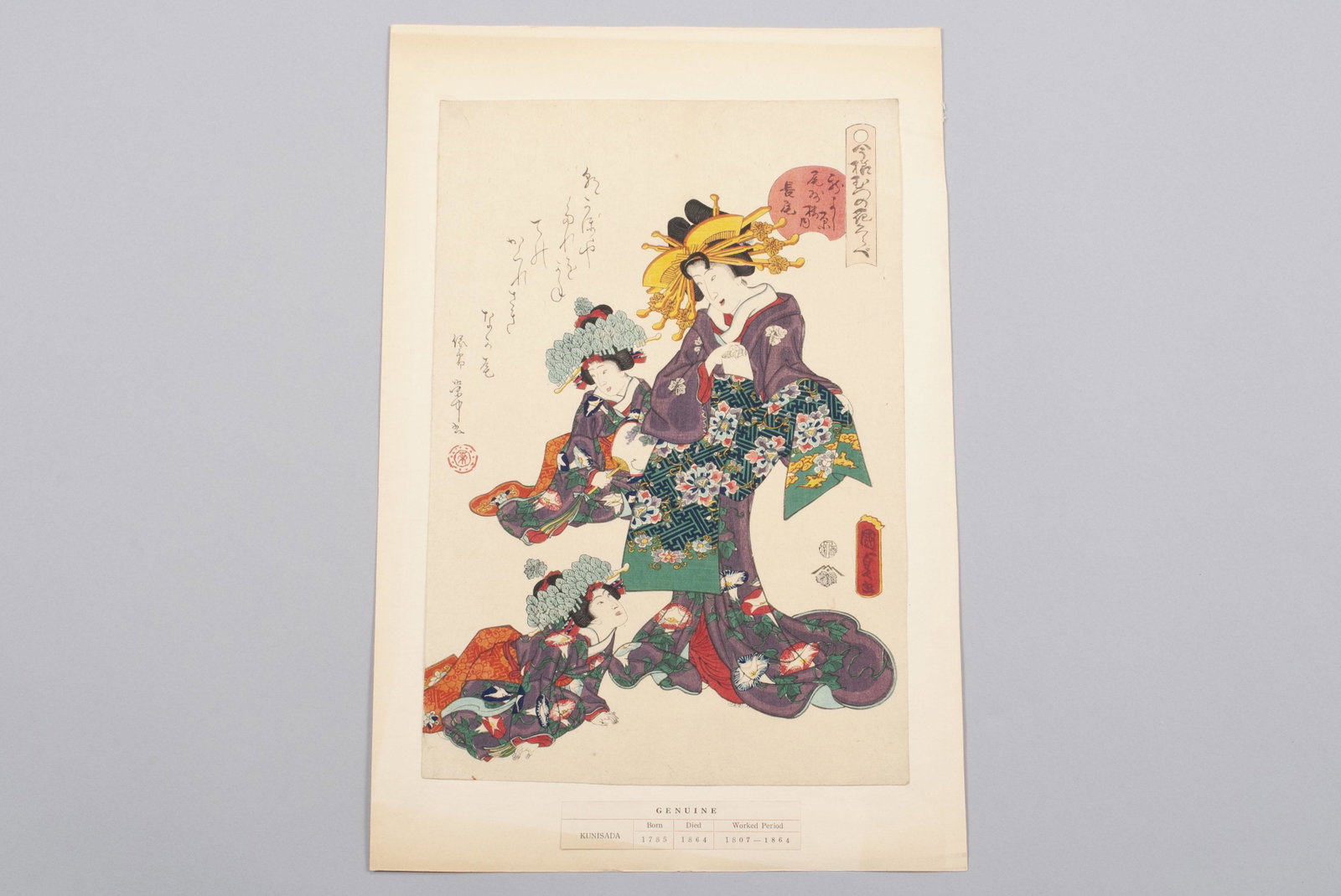 UTAGAWA KUNISADA (JAPANESE, 1785-1864): UTAGAWA KUNISADA (JAPANESE, 1785-1864) Ukiyo-e woodblock print, polychrome, depicting a lady with two younger girls, all dressed in matching mauve kimono. Mounted against paper. Impression: 14.75" hei