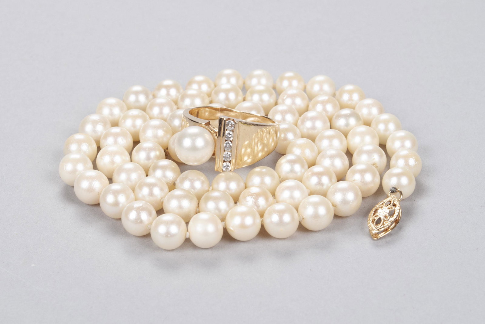 MIKIMOTO PEARL NECKLACE AND GOLD RING: MIKIMOTO PEARL NECKLACE AND GOLD RING Japan, Mid-20th century. Both pieces marked 14k. Strand of pearls with gold clasp together with pearl ring flanked by row of diamonds. Necklace 18" length