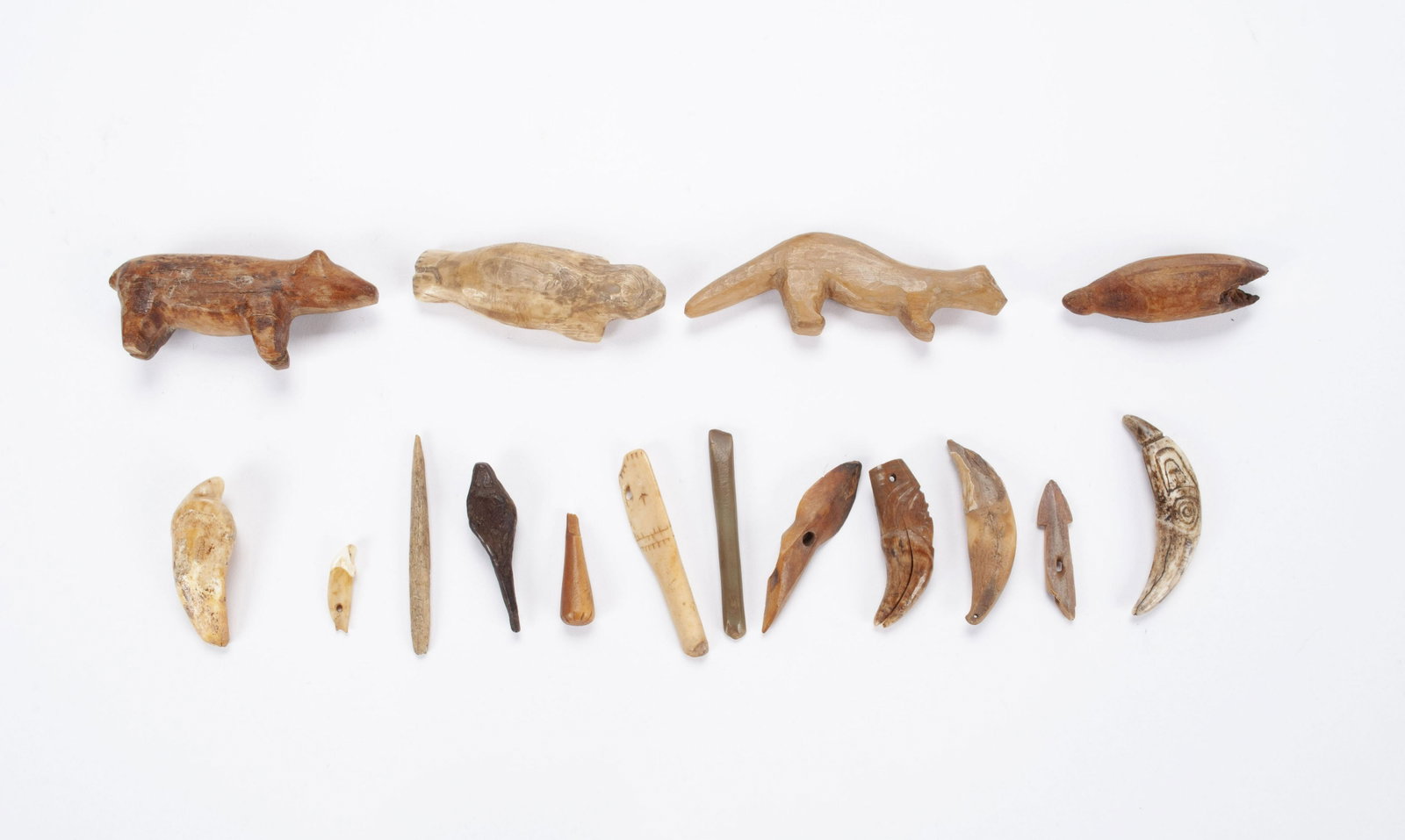 COLLECTION OF DIMINUTIVE INUIT CARVINGS: COLLECTION OF DIMINUTIVE INUIT CARVINGS Sixteen total articles, including animal forms as well as several carved and fossilized cave bear teeth, some made as pendants. Largest: 2" length