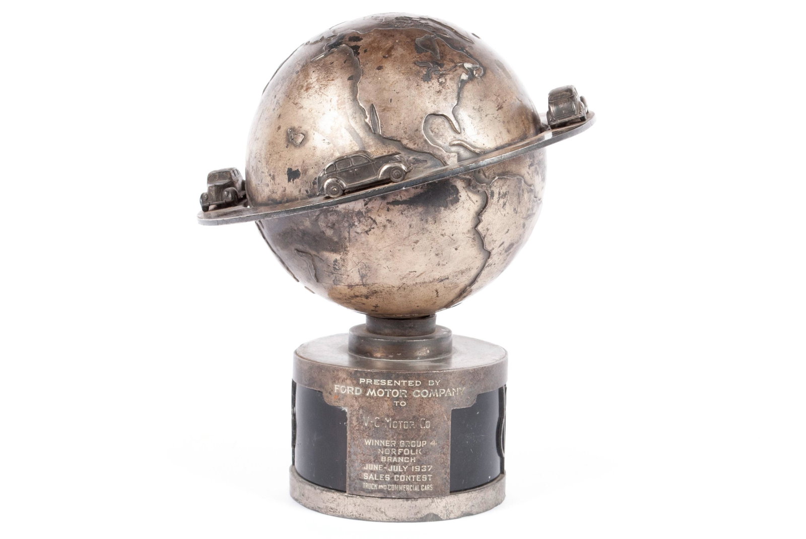 1937 FORD SALES AWARD TROPHY: 1937 FORD SALES AWARD TROPHY White metal globe showing the continents, encircled by ring decorated with four (4) Ford vehicles, resting on a cylindrical stand that reads "Presented by FORD MOTOR 