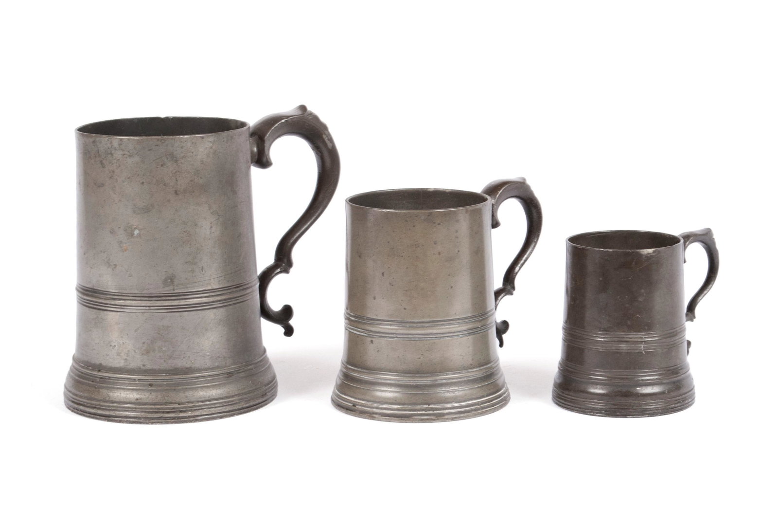 THREE PEWTER MEASURES WITH GLASS BOTTOMS: THREE PEWTER MEASURES WITH GLASS BOTTOMS England, 19th century. Half Pint, Pint and Quart size glass bottom measures or steins, quart marked for Watts & Harton of London, the pint hallmarked (sic). 3 