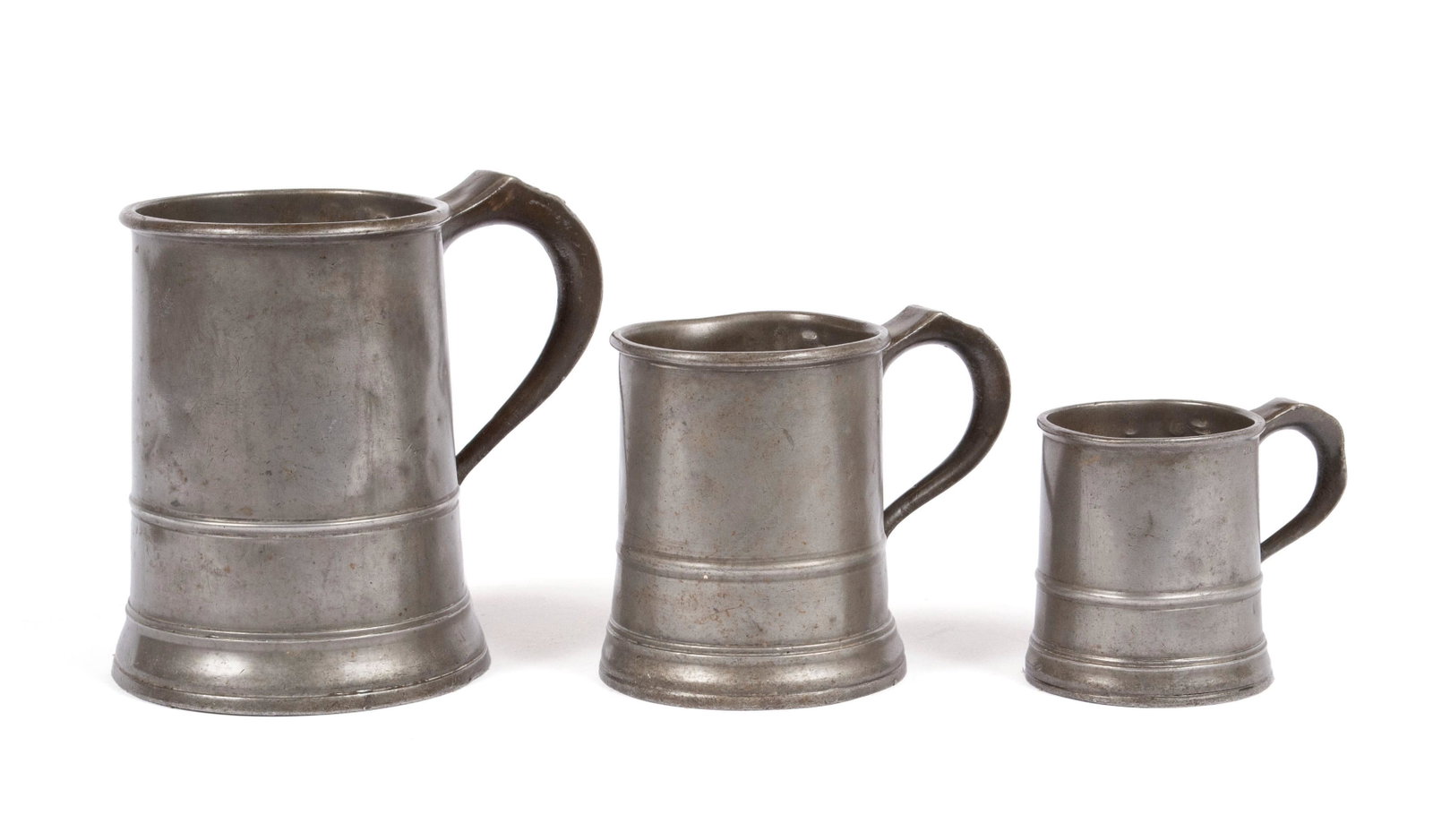 THREE VICTORIAN PEWTER GRADUATED MEASURES: THREE VICTORIAN PEWTER GRADUATED MEASURES England, circa 1890. Half Pint, Pint, Quart, VR and touchmarks under rim, set shows age wear. 3 1/4 in. (8.26 cm.) to 6 in. (15.24 cm.)
