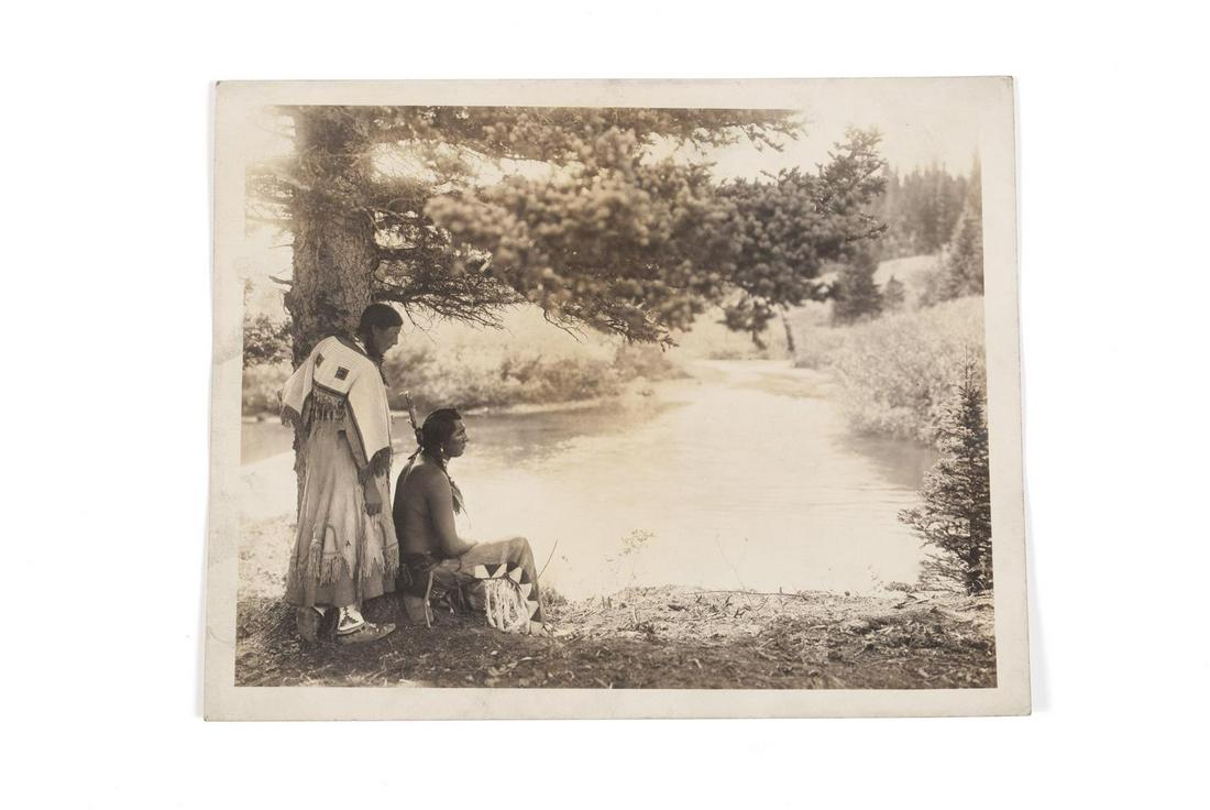 ATTRIBUTED TO ROLAND REED (AMERICAN, 1864-1934): ATTRIBUTED TO ROLAND REED (AMERICAN, 1864-1934) Late 19th/early 20th century, silver gelatin print. Fish Wolf Robe and Princess Dawn Mist of the Blackfoot tribe on the banks of the Cutbank River in Gl