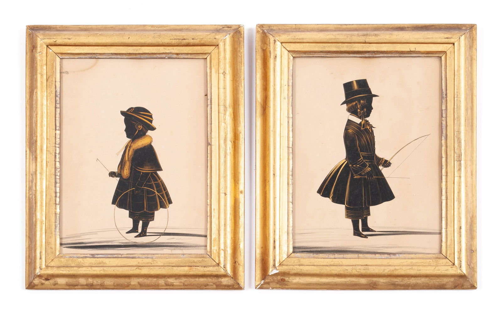 PAIR OF CHILD'S SILHOUETTE PORTRAITS: PAIR OF CHILD'S SILHOUETTE PORTRAITSMid-19th century. Opposing renderings of young boy and girl, one with a bow and arrow, the other with a hoop and stick, with gilt highlights throughout. Identically