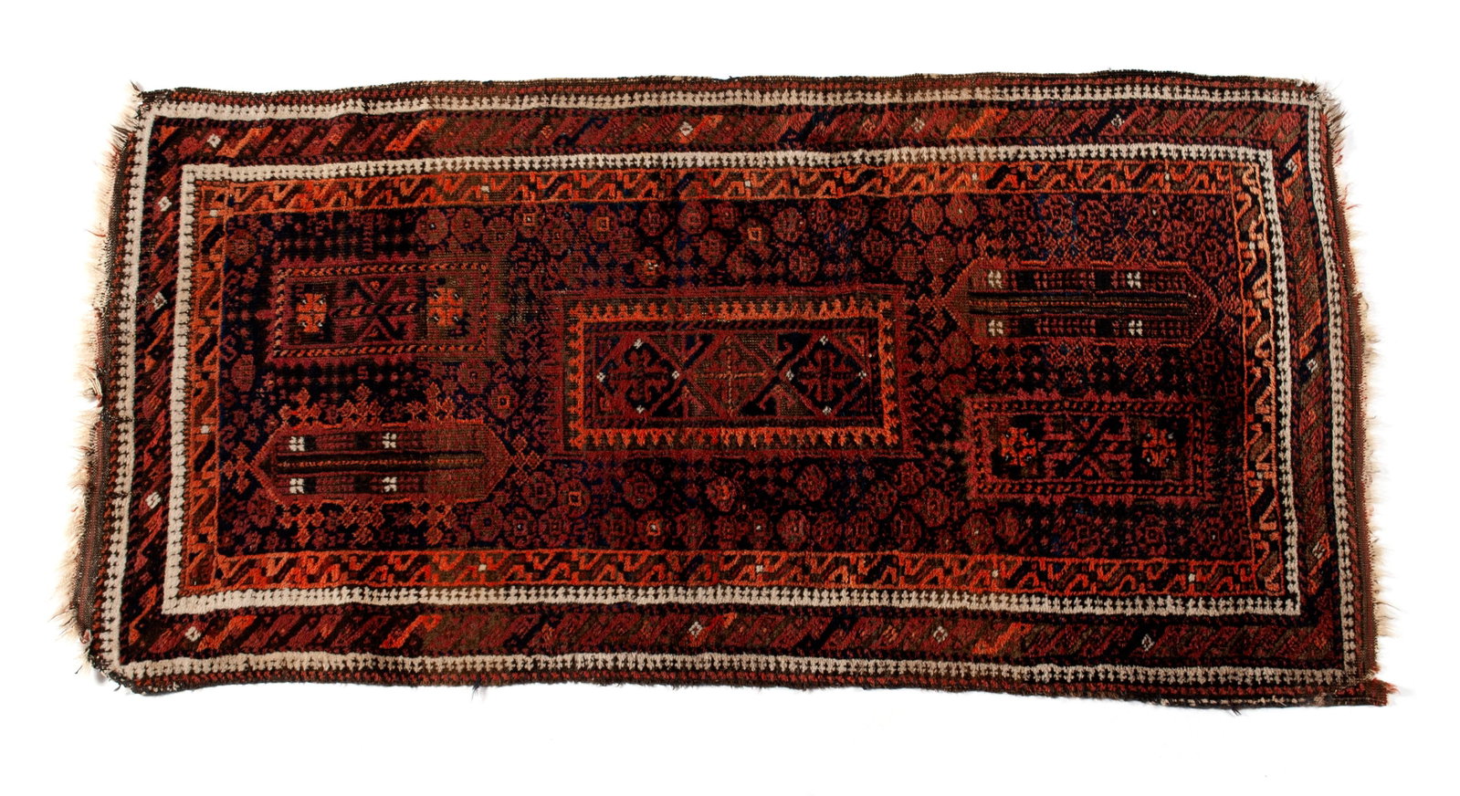 BALUCH AREA RUG: BALUCH AREA RUG Persian, mid-20th century. Brown, red, and orange panels and foliate designs on the near black field, matching borders with ivory guard borders. 4 ft. 9 ibn. x 2 ft. 6 in.
