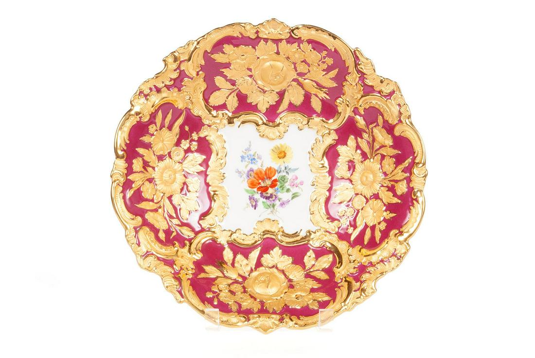 MEISSEN GILT PORCELAIN CENTREBOWL: MEISSEN GILT PORCELAIN CENTREBOWLGerman, late 19th/early 20th century. The articulated and relief-molded rim surrounding four cartouches with gilt floral and filigree design over cranberry ground, the