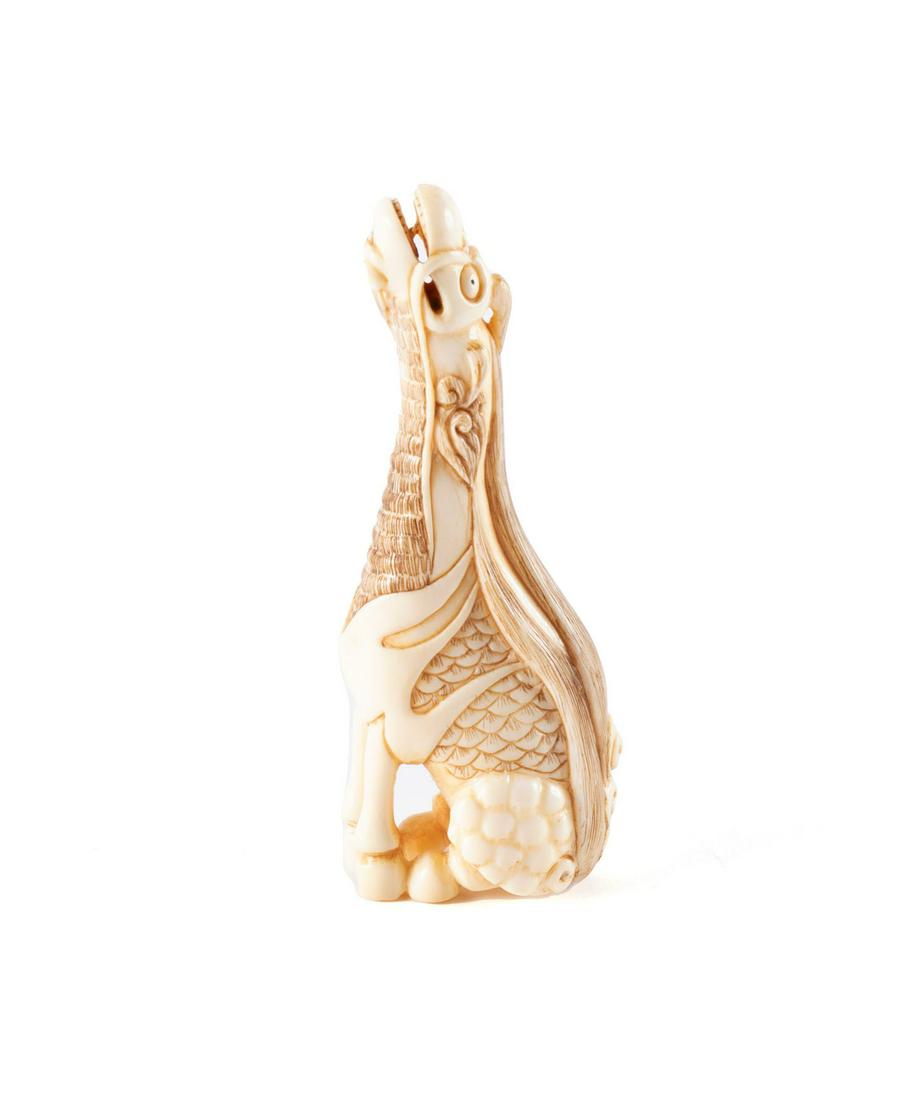 FINELY CARVED KIRIN NETSUKE: FINELY CARVED KIRIN NETSUKE Japanese, early 20th century, organic material. The seated figure with neck extended upwards, jaws ajar; signed underfoot. 3 1/4 in. (8.3 cm.)