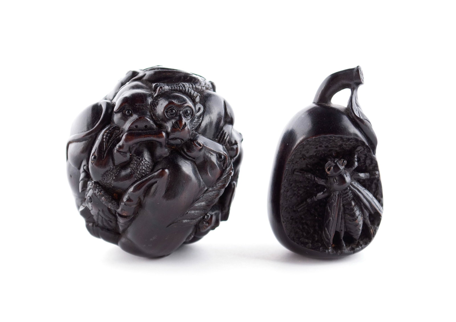 COMPANION LACQUERED OKIMONO AND NETSUKE: COMPANION LACQUERED OKIMONO AND NETSUKE Japanese, mid 20th century, ebonized wood. Nagoya School influenced carved Junishi zodiac ball together with a carved wasp resting on pear, after the type made 