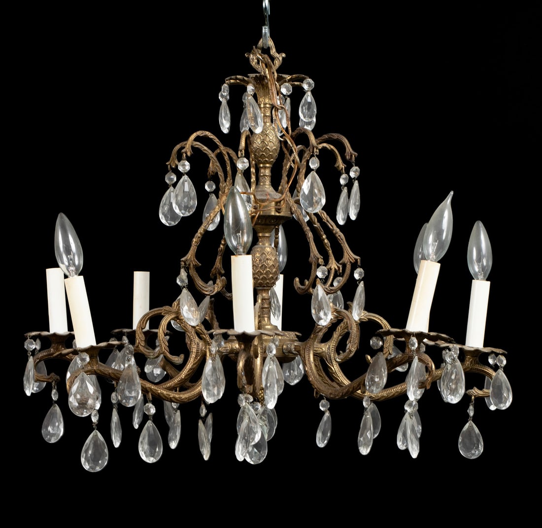 EIGHT-LIGHT GILT METAL CHANDELIER: EIGHT-LIGHT GILT METAL CHANDELIER Continental, 20th century. Scrolling arms hold the candlestick form electric fixtures adorned with drop prisms. 21 x 25 in. (53.3 x 63.5 cm.)