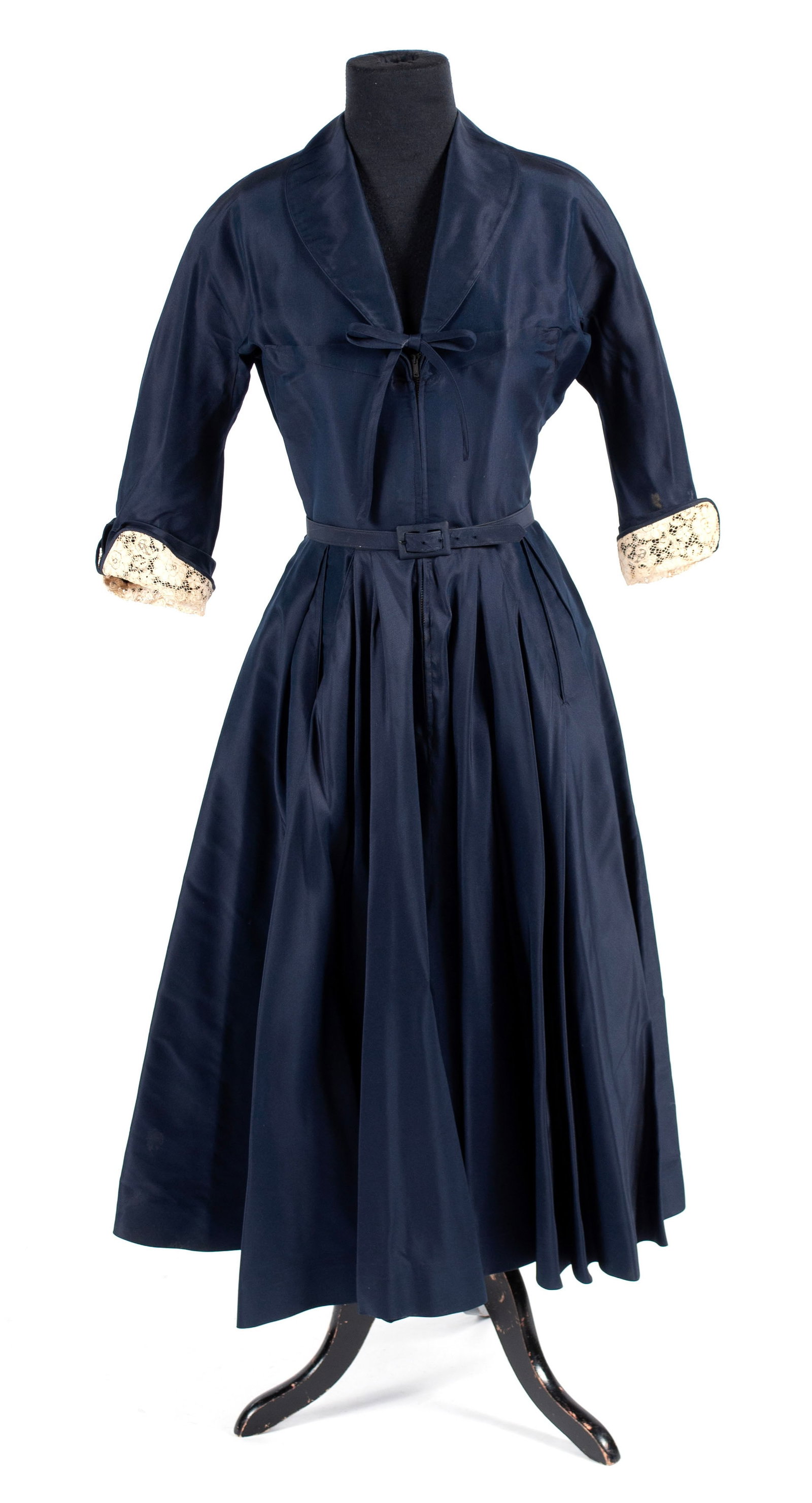 LARRY ALDRICH NEW YORK FRONT ZIP DRESS: LARRY ALDRICH NEW YORK FRONT ZIP DRESS Circa 1950s cocktail dress in navy with pleated skirt, belt closure, and lace-trimmed sleeves. Length: 47 in. (119.4 cm.), shoulders: 14 in. (35.6 cm.), sleeves 