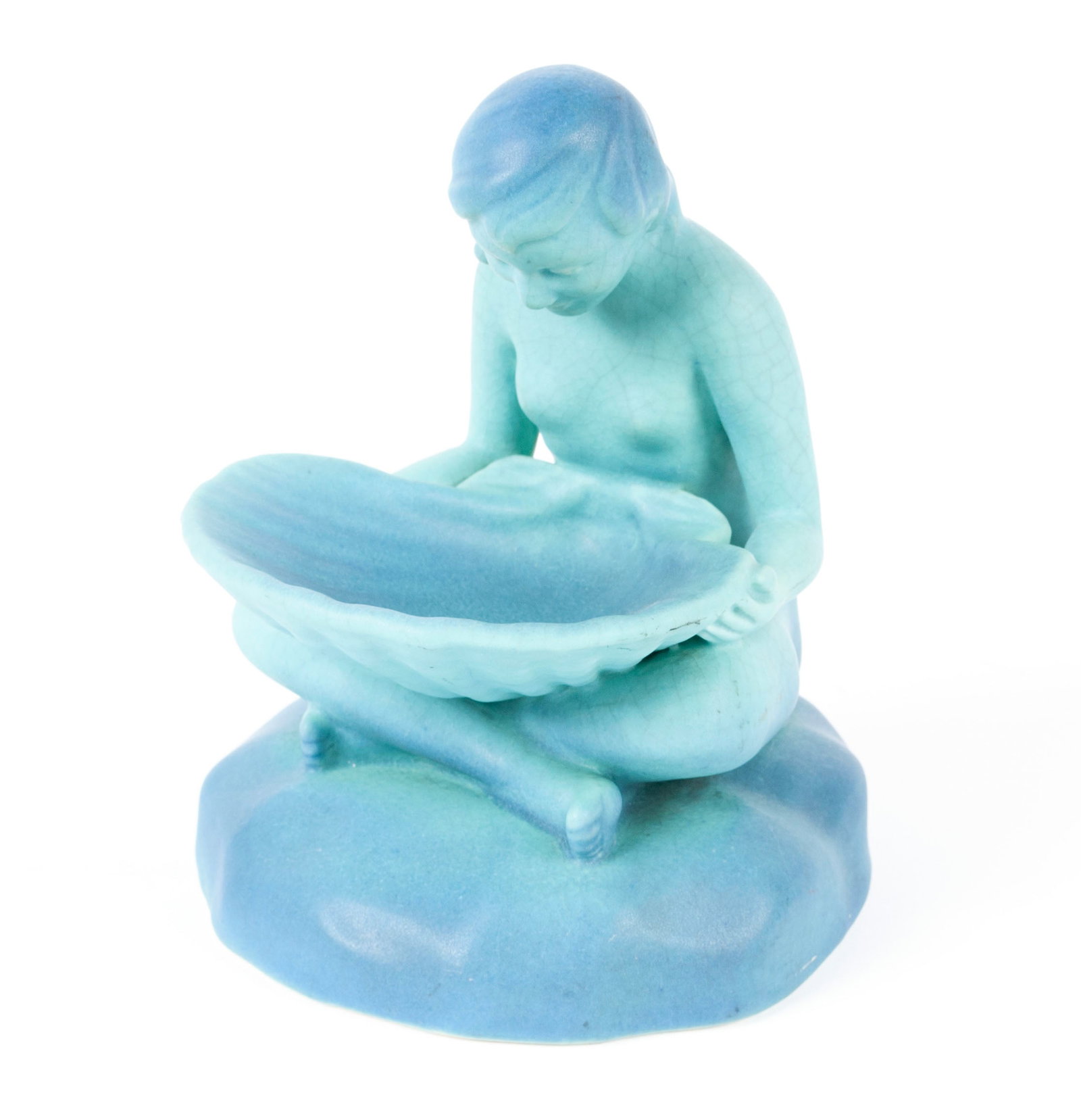 VAN BRIGGLE SHELL GIRL: VAN BRIGGLE SHELL GIRLAmerican, Circa 1930's, unsigned. Pottery model of a seated girl holding shell in "Ming Blue" glaze.7 in. (17.8 cm.)