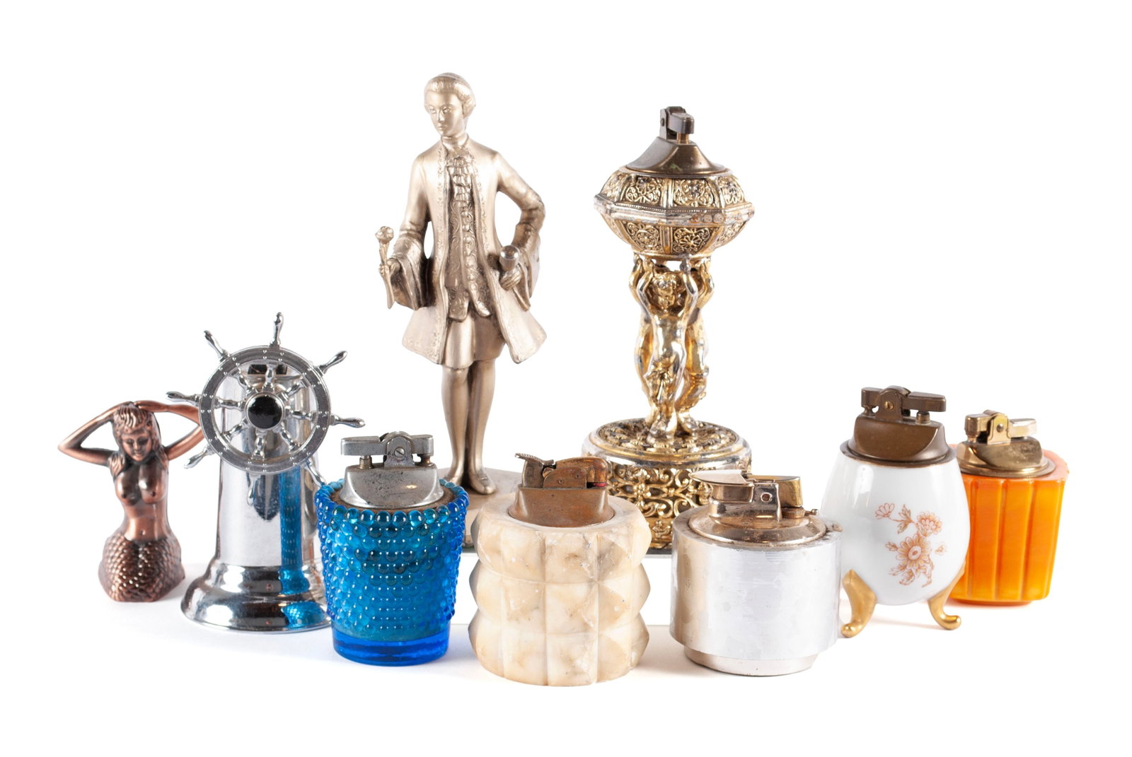 COLLECTION OF LIGHTERS: COLLECTION OF LIGHTERS Nine (9) pieces. Includes a chrome ship's wheel, full length colonial figure, triple-cherub supported lighter, orange Bakelite lighter, off-white mineral lighter, Limoges porcel