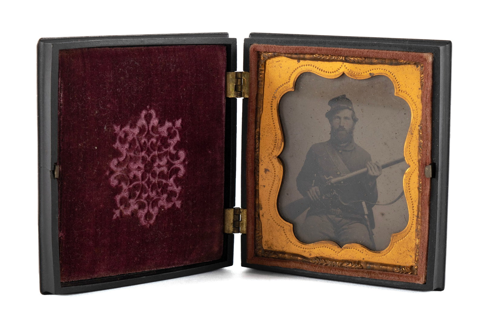 TIN TYPE CIVIL WAR PHOTOGRAPH OF A UNION SOLDIER: TIN TYPE CIVIL WAR PHOTOGRAPH OF A UNION SOLDIER American, Circa 1860's, Tin type photograph of a seated Union soldier holding rifle with bayonet attached to belt with U.S. belt plate contained in a f