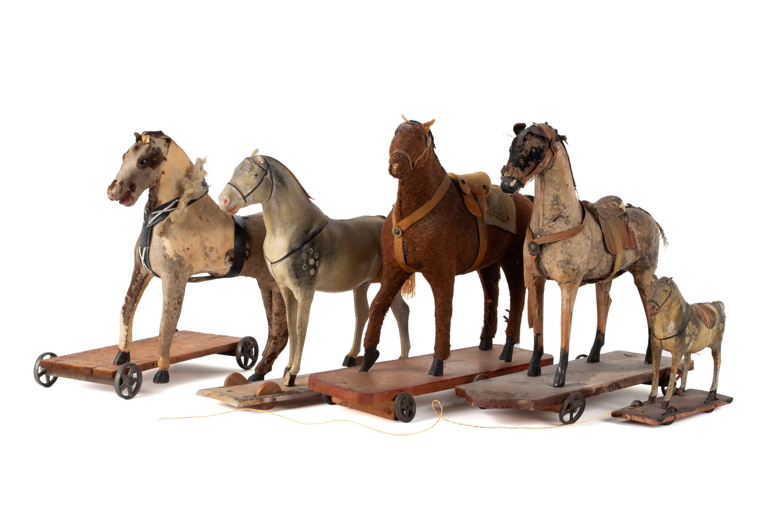 FIVE CHILD'S HORSE PULL TOYS: FIVE CHILD'S HORSE PULL TOYS19th/20th century. Assorted sizes, several covered in animal skin, another of papier m?ch?, on wooden platforms with wheels.Largest: 12 x 12 1/2 x 5 in. (30.5 x 31.8 x 12.7