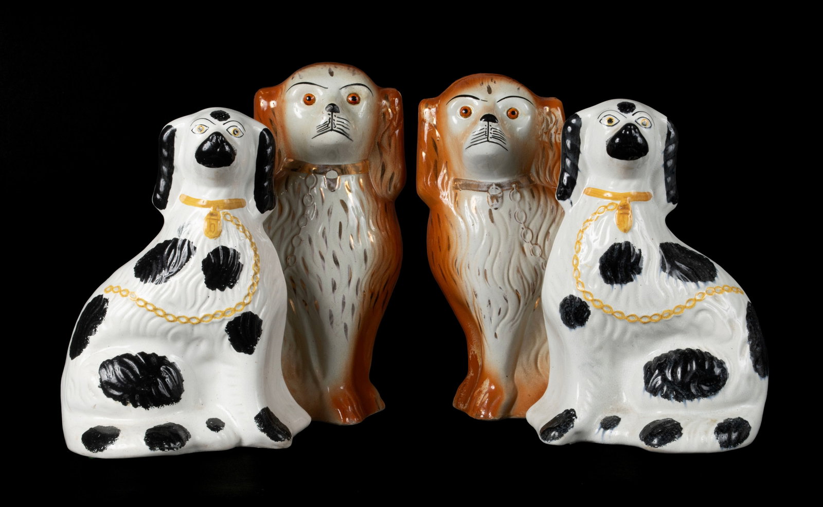 STAFFORDSHIRE PORCELAIN DOGS: STAFFORDSHIRE PORCELAIN DOGS English, circa 1900, porcelain. Four (4) pieces in two pair, the taller pair with amber highlights, the other pair with black spots on white. Largest: 14 1/4 x 10 in. (36.