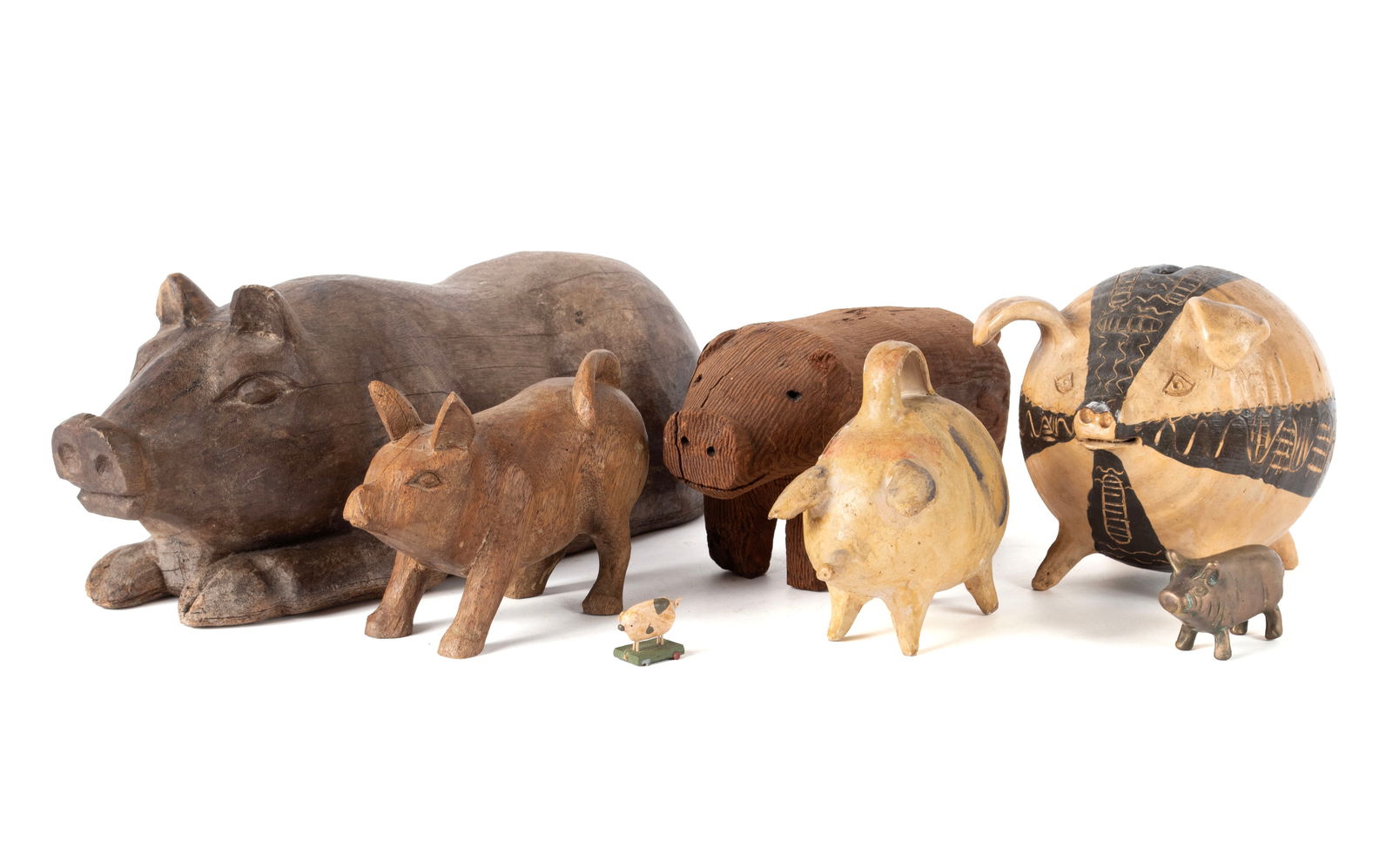 COLLECTION OF FOLK ART PIGS: COLLECTION OF FOLK ART PIGS20th century. Including three (3) wooden carved pig figures, two (2) ceramic pig banks - one signed 'Gilliam' - a miniature metal pig figure and a miniature pig pull toy.Lar