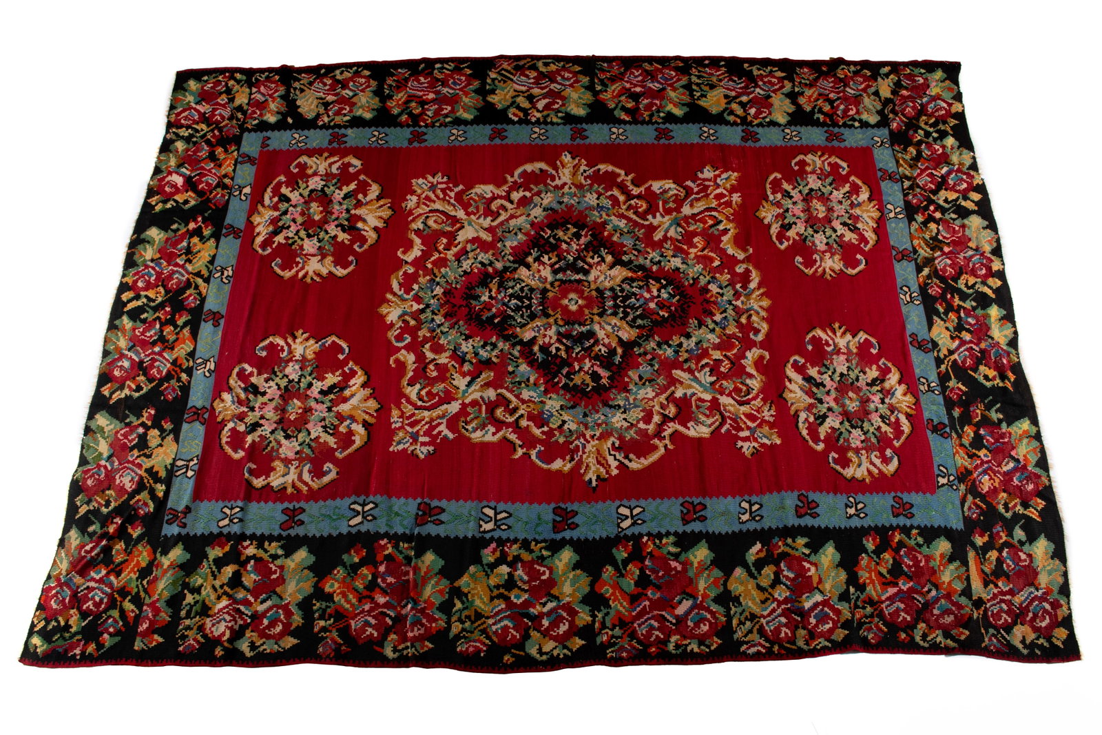 TURKISH KILIM RUG: TURKISH KILIM RUG Turkish, 20th century. Large central colorful floral bouquet centers the red field, with matching floral bouquets to each corner of the red field, showing an inner blue border and a 