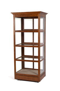 OAK DISPLAY CABINET: OAK DISPLAY CABINETAmerican, circa 1900. Rectangular, glass paneled oak cabinet, with three interior glass shelves, sliding door access to each of the four display shelves, on wheels.73 x 32 1/2 x 25