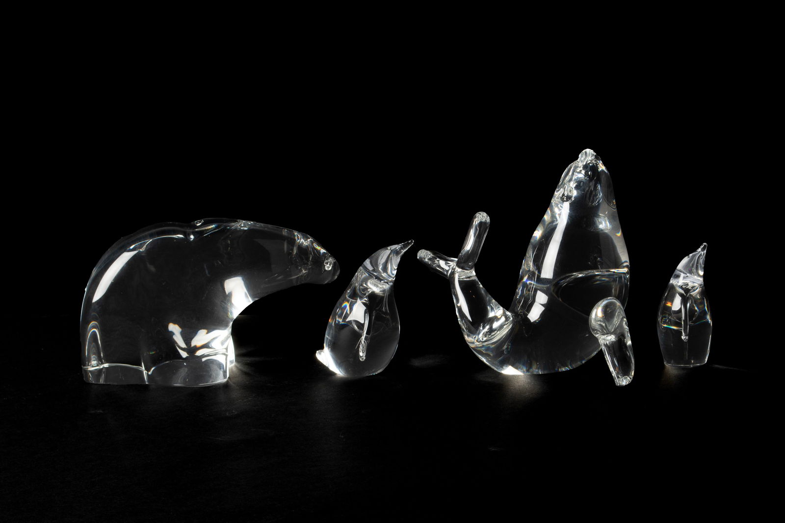 FOUR STEUBEN FIGURAL ANIMAL GLASS SCULPTURES: FOUR STEUBEN FIGURAL ANIMAL GLASS SCULPTURESAmerican, 20th century. Four (4) crystal figural sculptures, a bear, a seal, and two (2) penguins.Bear: 5 1/4 in. (13.3 cm.), Seal: 4 in. (10.2 cm.)