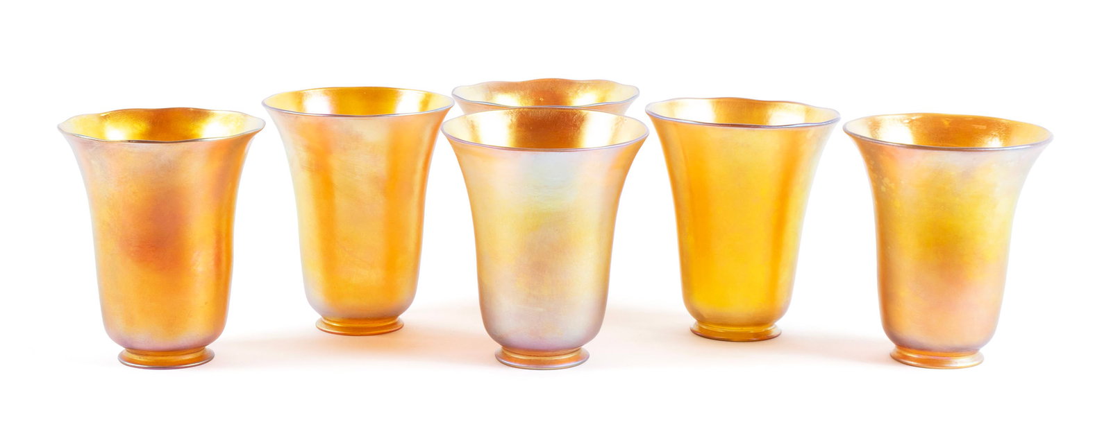 SET OF SIX STEUBEN GOLD AURENE GLASS SHADES: SET OF SIX STEUBEN GOLD AURENE GLASS SHADESAmerican, 1903-1933. Set of six (6) bell form lamp shades with acid etched fleur de lis marks.5 3/4 x 4 3/4 in. (14.6 x 12.1 cm.)