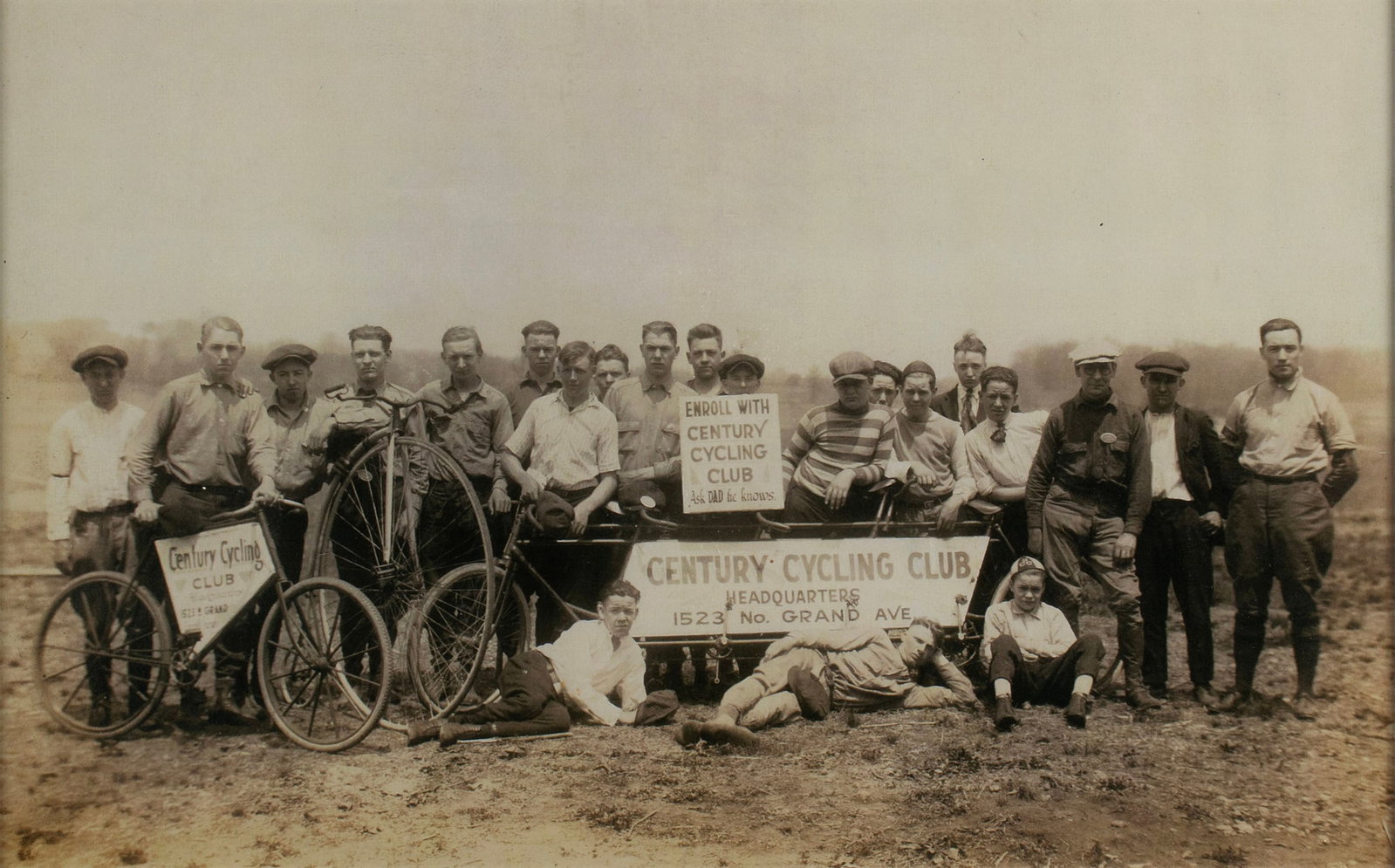 CENTURY CYCLING CLUB PHOTOGRAPH: CENTURY CYCLING CLUB PHOTOGRAPH Early 20th century. Group photograph against an open landscape, likely in St. Louis, Missouri. Central signage reading "CENTURY CYCLING CLUB - Headquarters - 1523 No. G