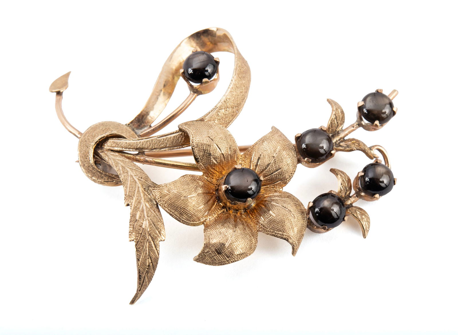 GOLD BOUQUET BROOCH: GOLD BOUQUET BROOCH A 14k yellow gold floral brooch set with six (6) round black star sapphires measuring approximately 4.7mm each. 2 x 1 1/2 in. (5.1 x 3.8 cm.); 7 grams