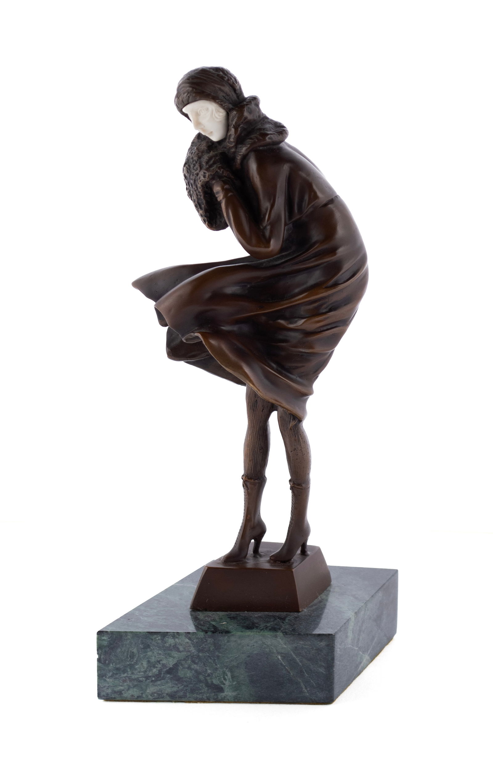 BRONZE IN THE MANNER OF CHIPARUS: BRONZE IN THE MANNER OF CHIPARUS 20th century, unsigned. Woman in a wind-blown coat, holding a muff, on green marble base. Height: 12 1/4 in. (31.1 cm.)