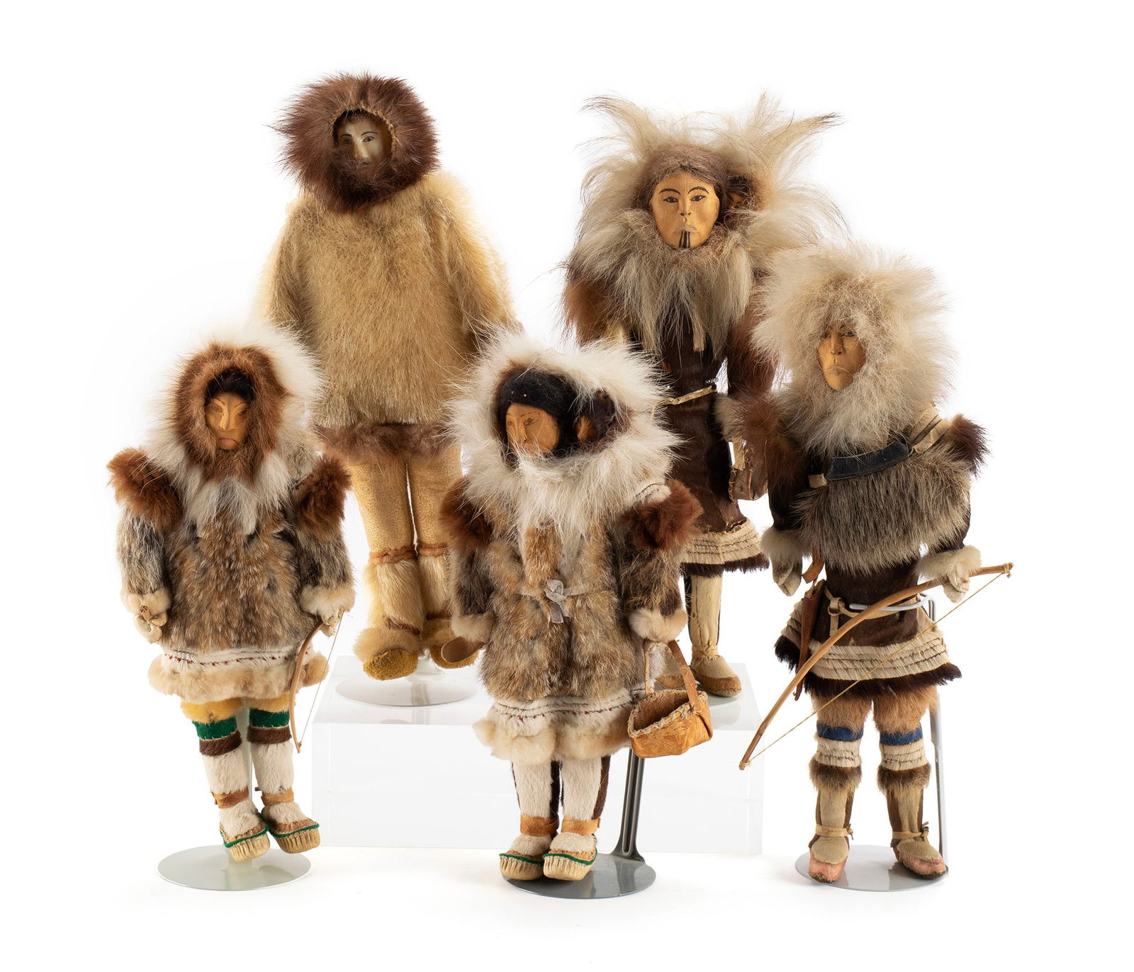 FIVE INUIT DOLLS: FIVE INUIT DOLLSAlaskan, 20th century. Five (5) dolls, two (2) pair showing carved wood faces depicting fathers with bow and mothers with child on shoulder holding basket, together with single figure